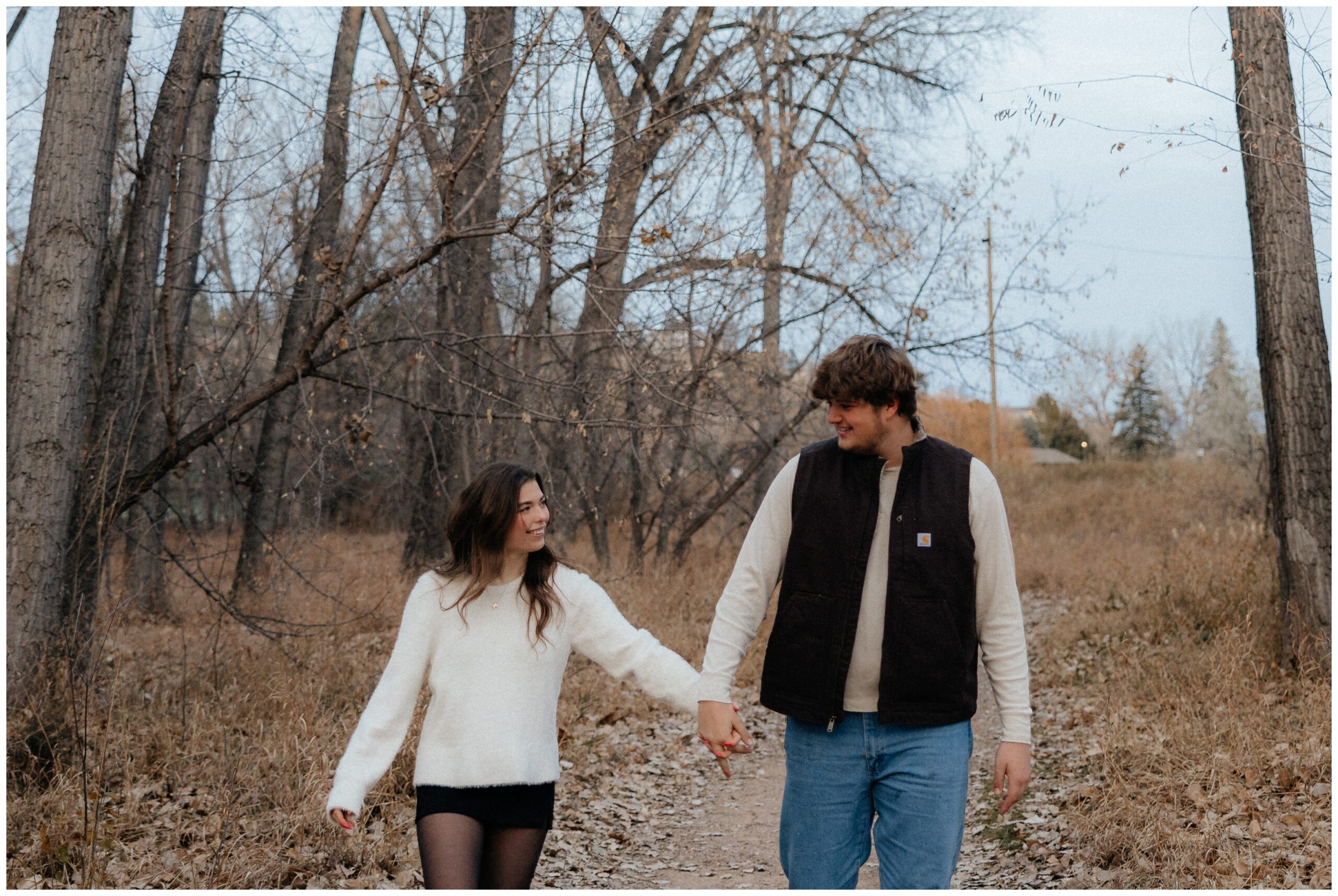 A couple talking down a trail holding hands.