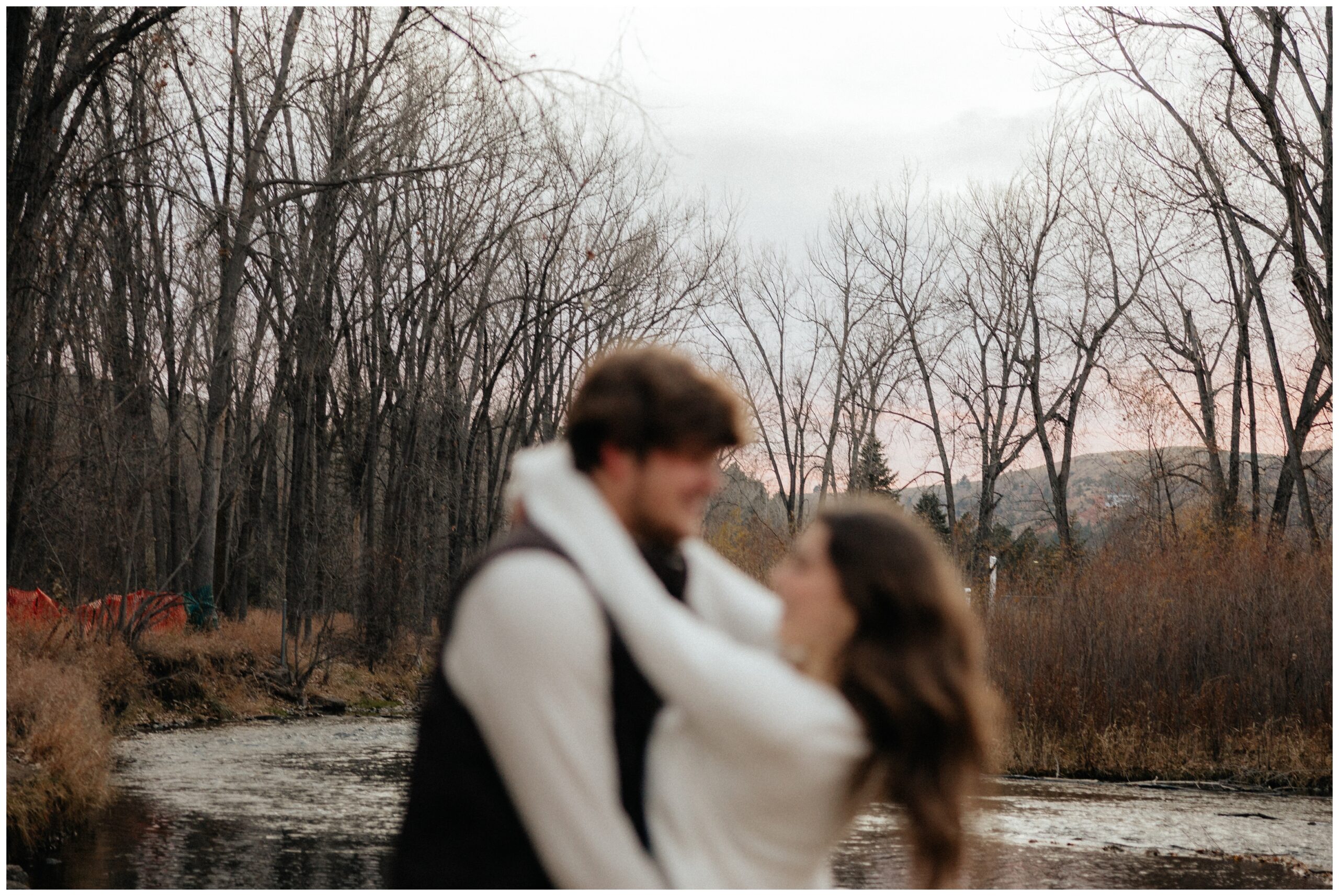 A couple standing in front of a creek.