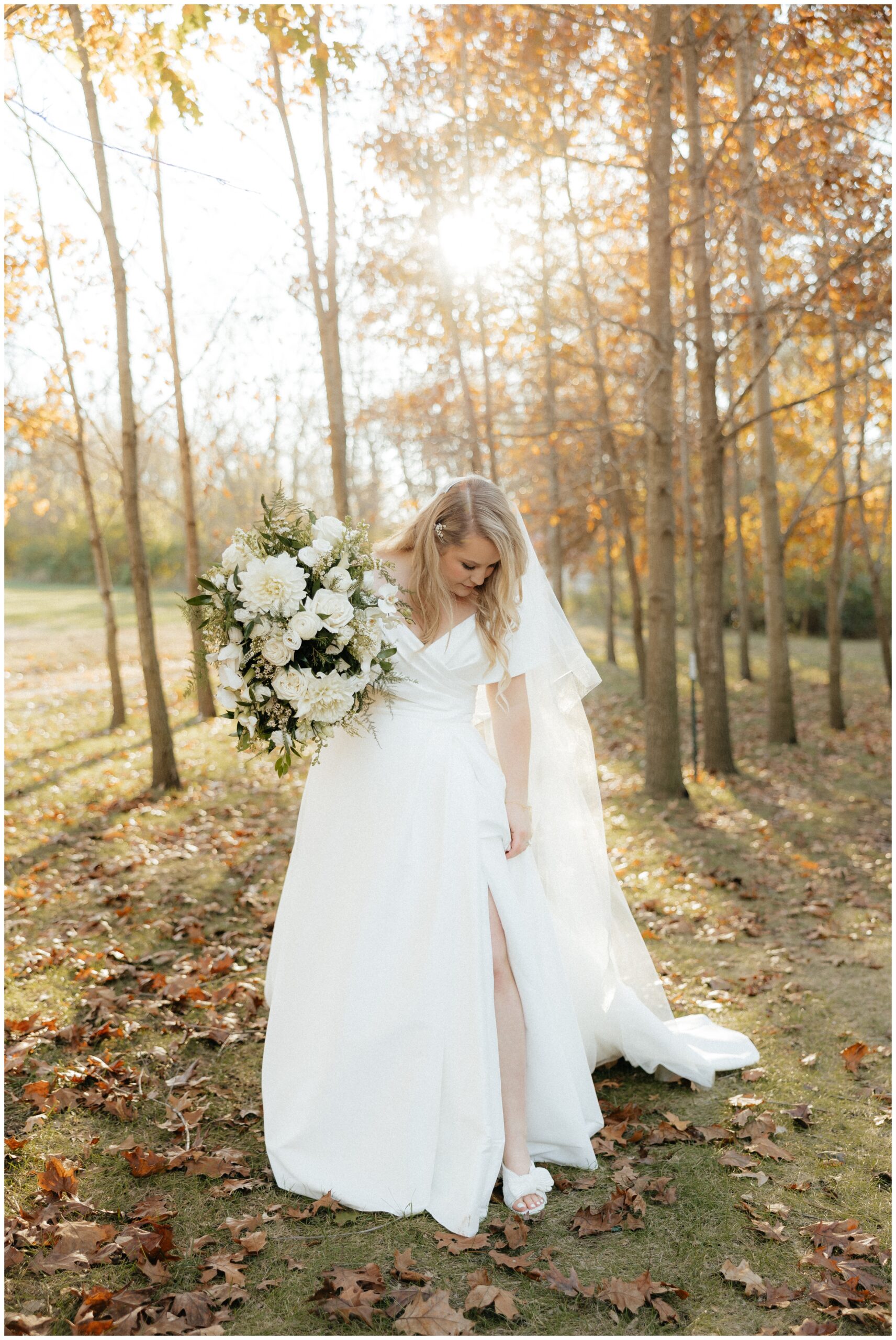 The bride looking down at the slit in her dress.