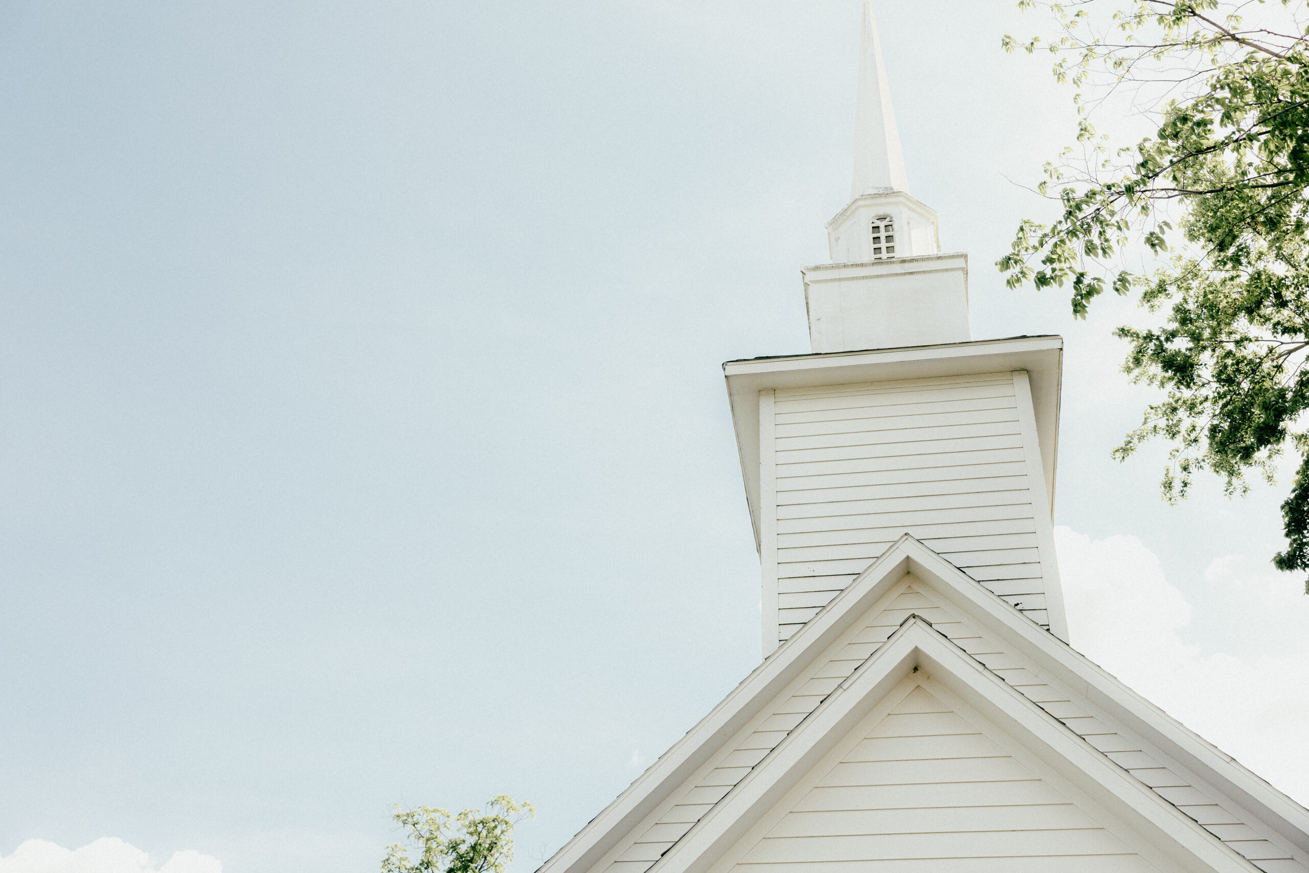 A chapel steeple in front of a cloudy sky.