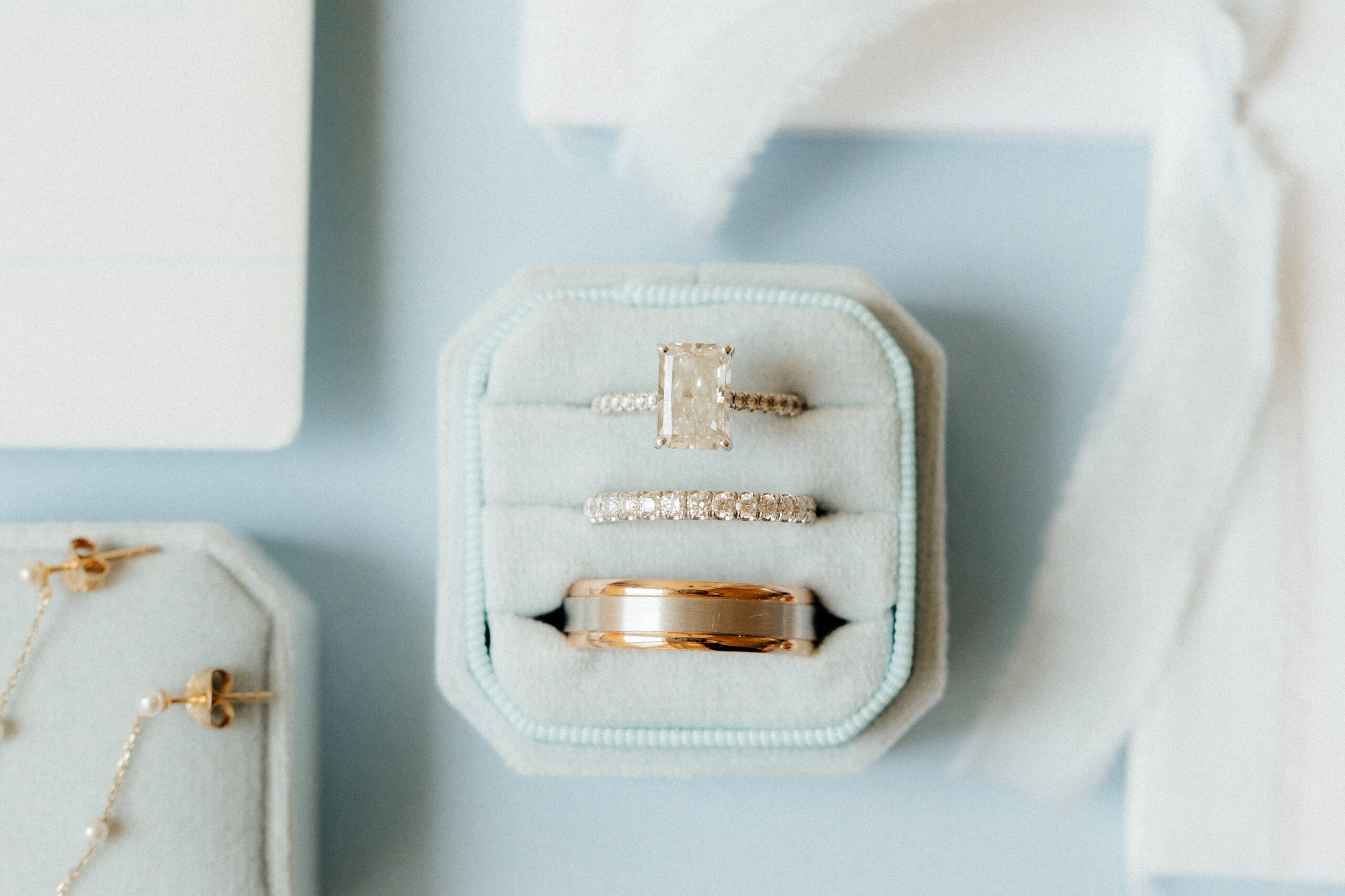 A beautiful engagement diamond ring and wedding bands in a soft blue ring box.