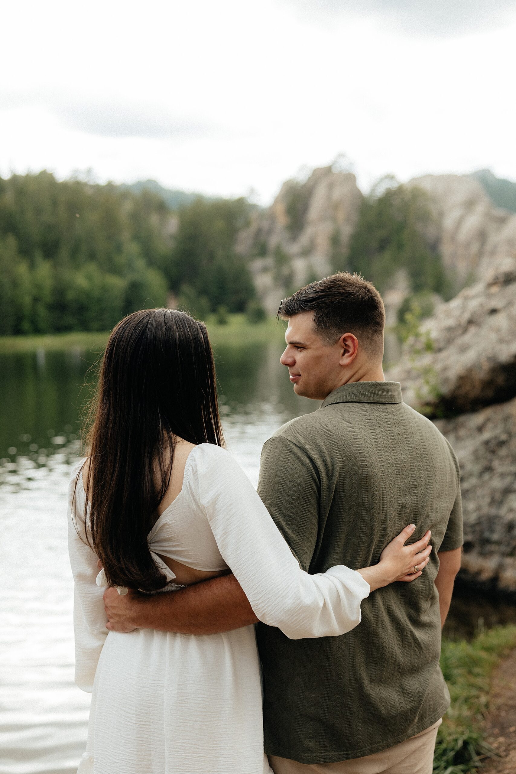 Harrison and Emily smiling at each other with the lake in the background.