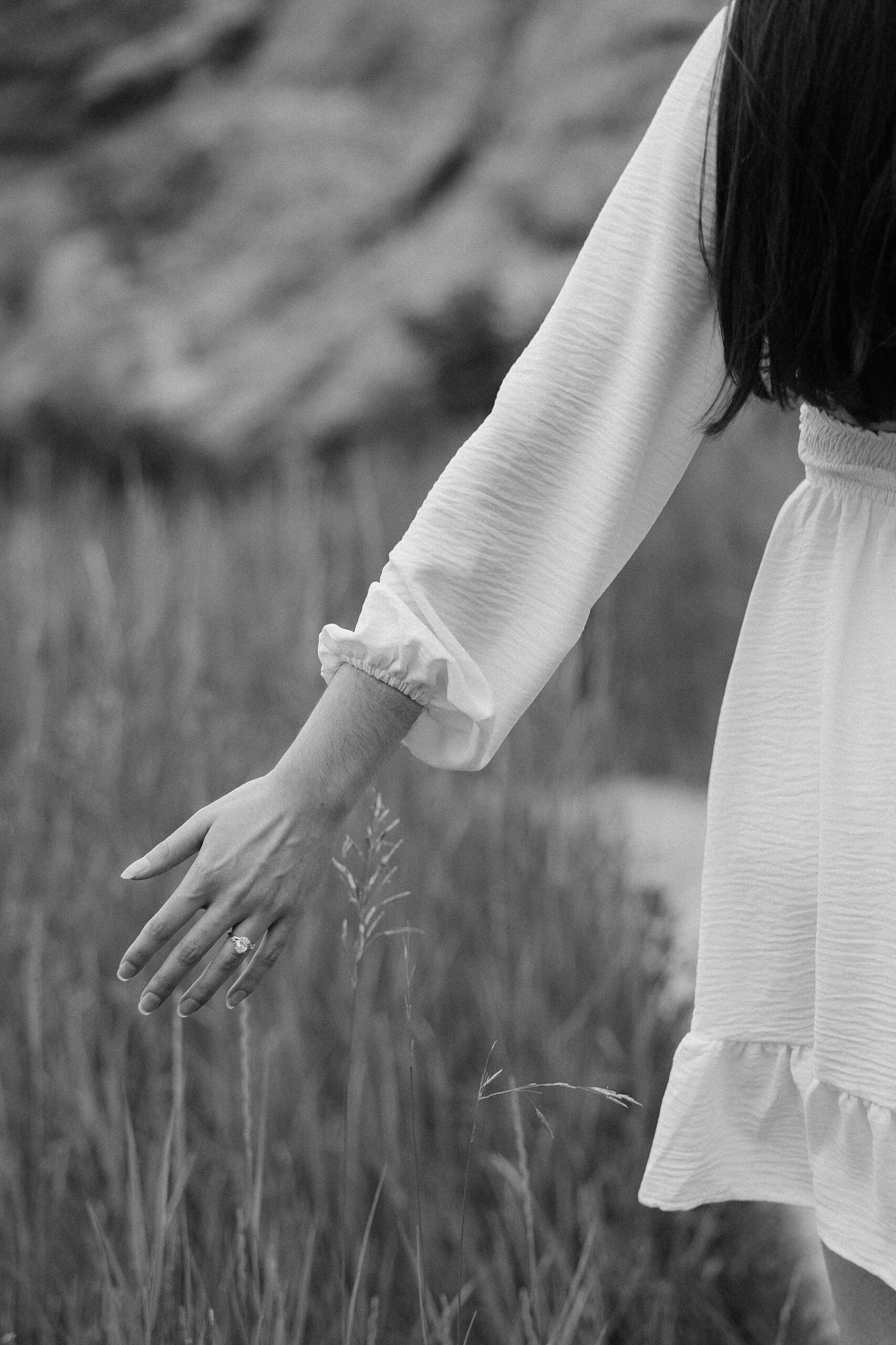 Emily runs her fingers through the grass as she and Harrison walk hand in hand.