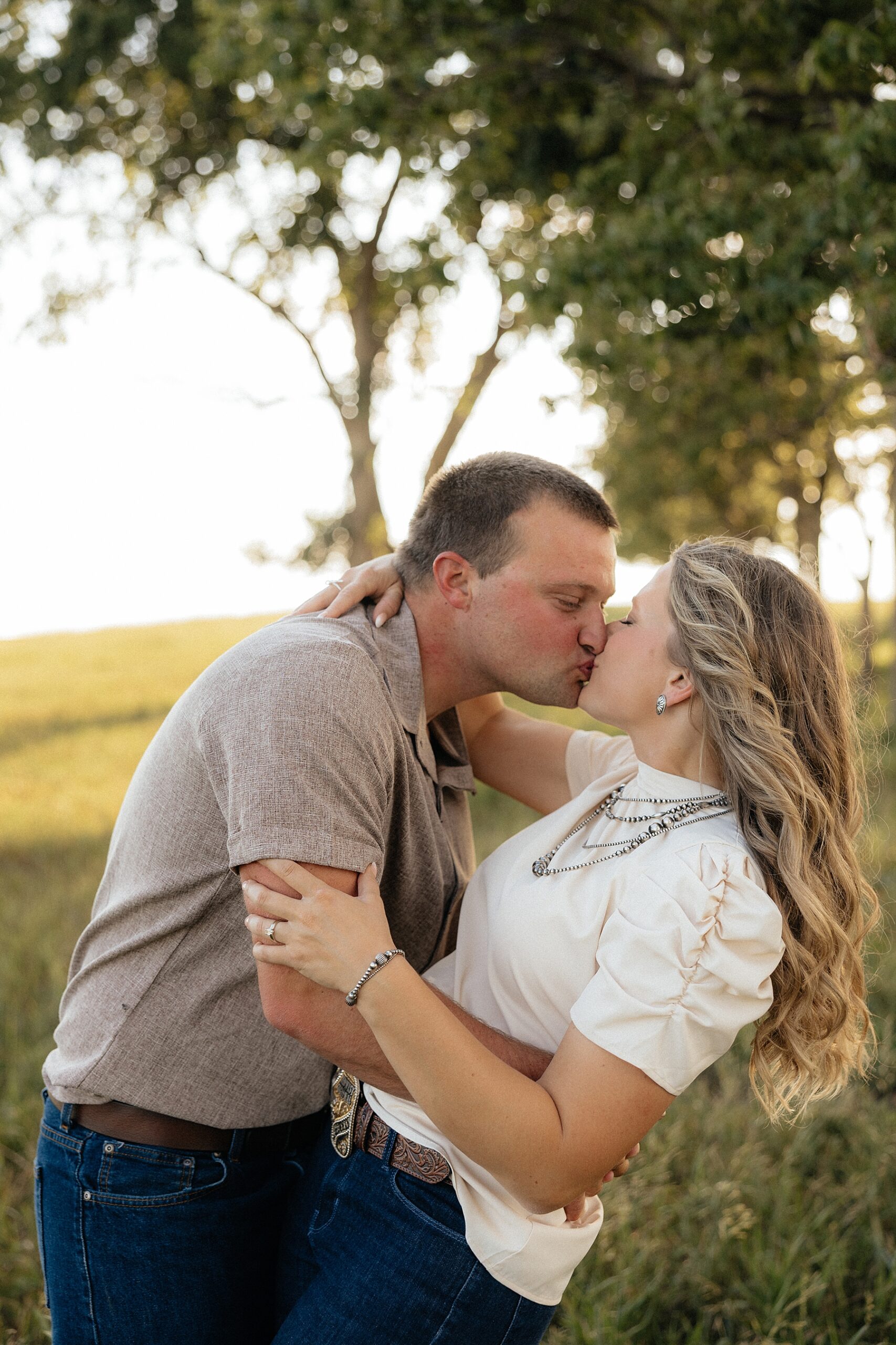 A couple kissing in a field.