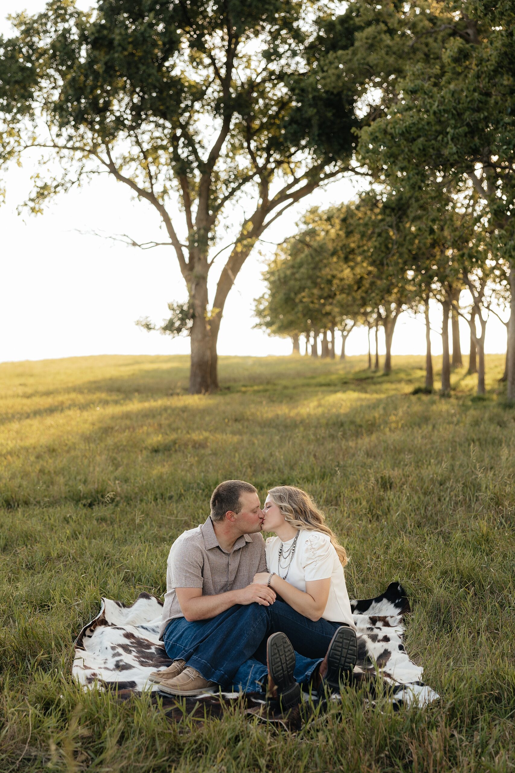 A couple sitting on a cowhide rug.