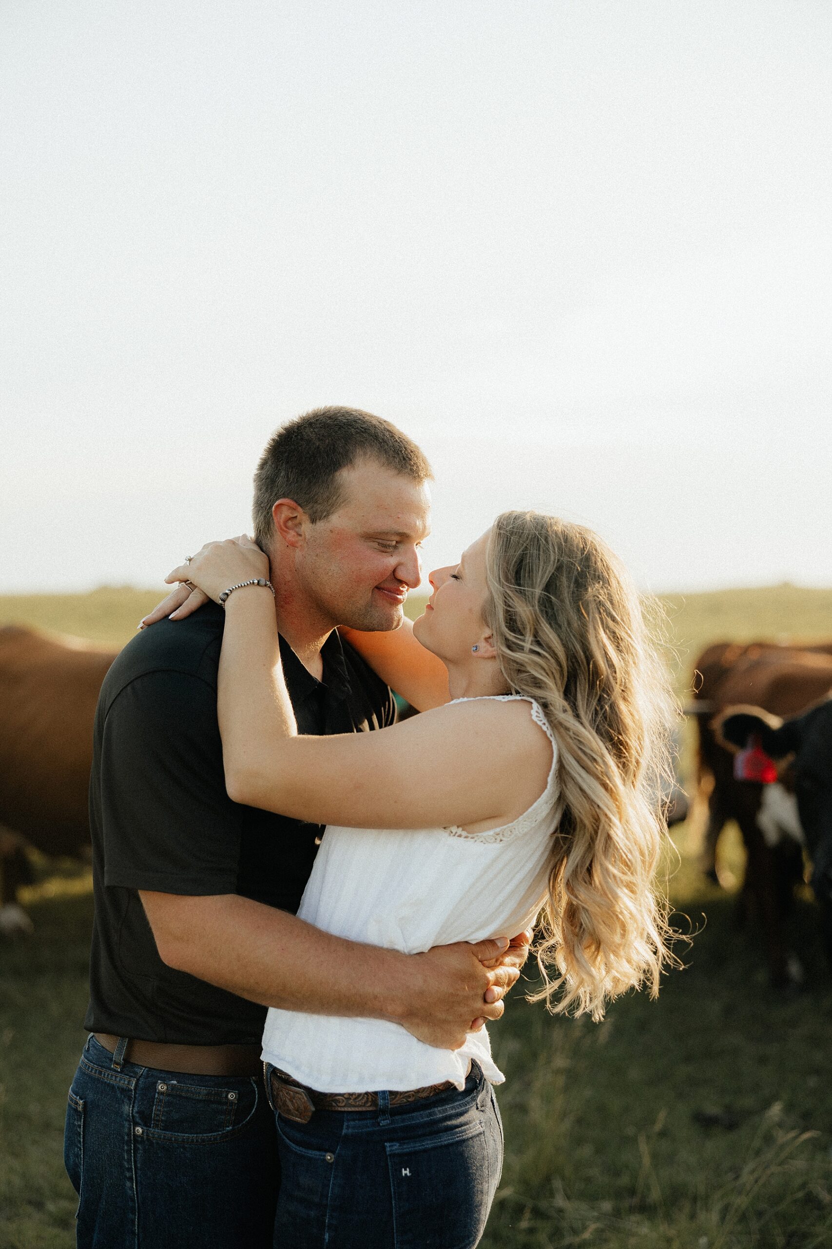 A couple in a field with cattle behind them.