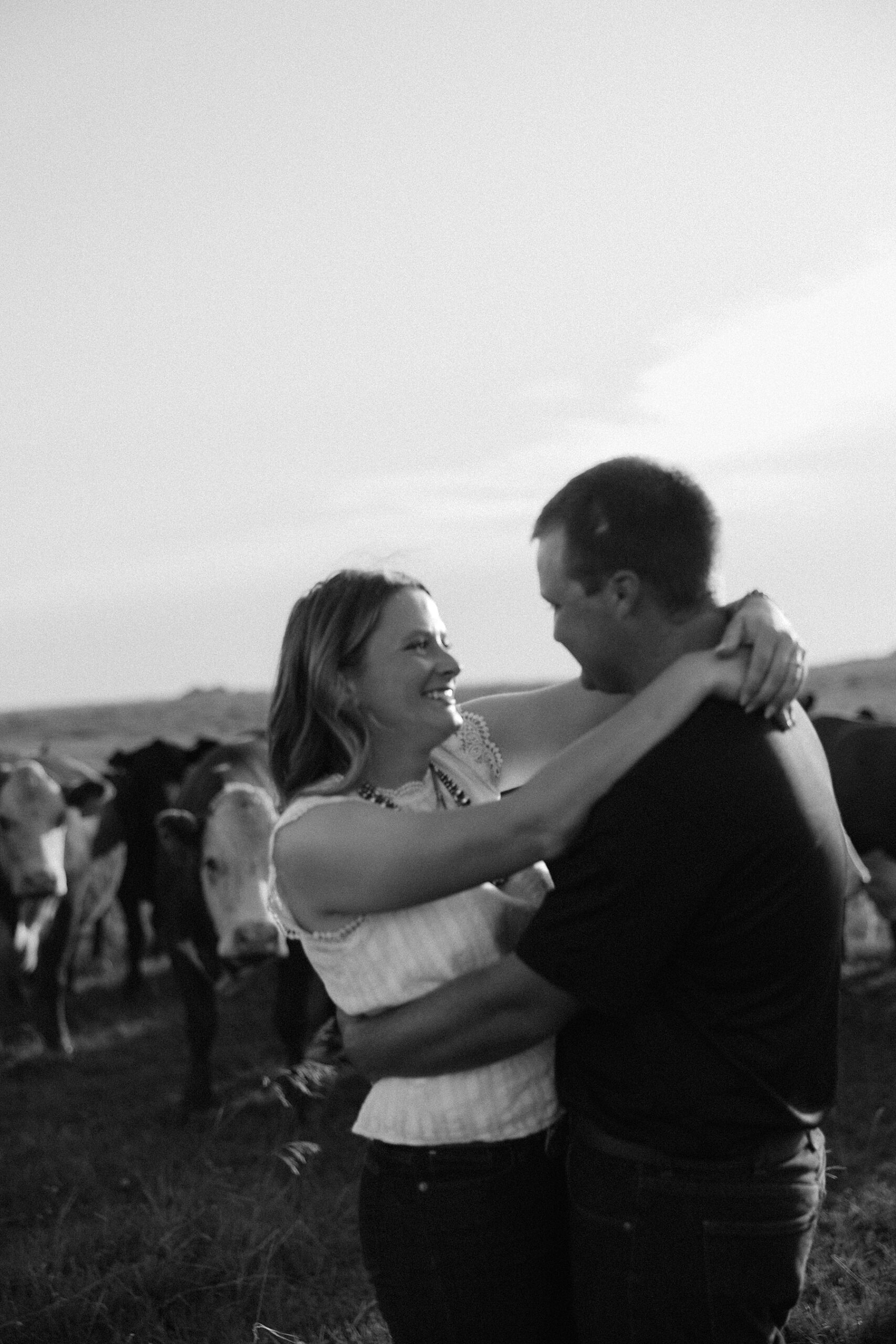 A couple in a field with cows.