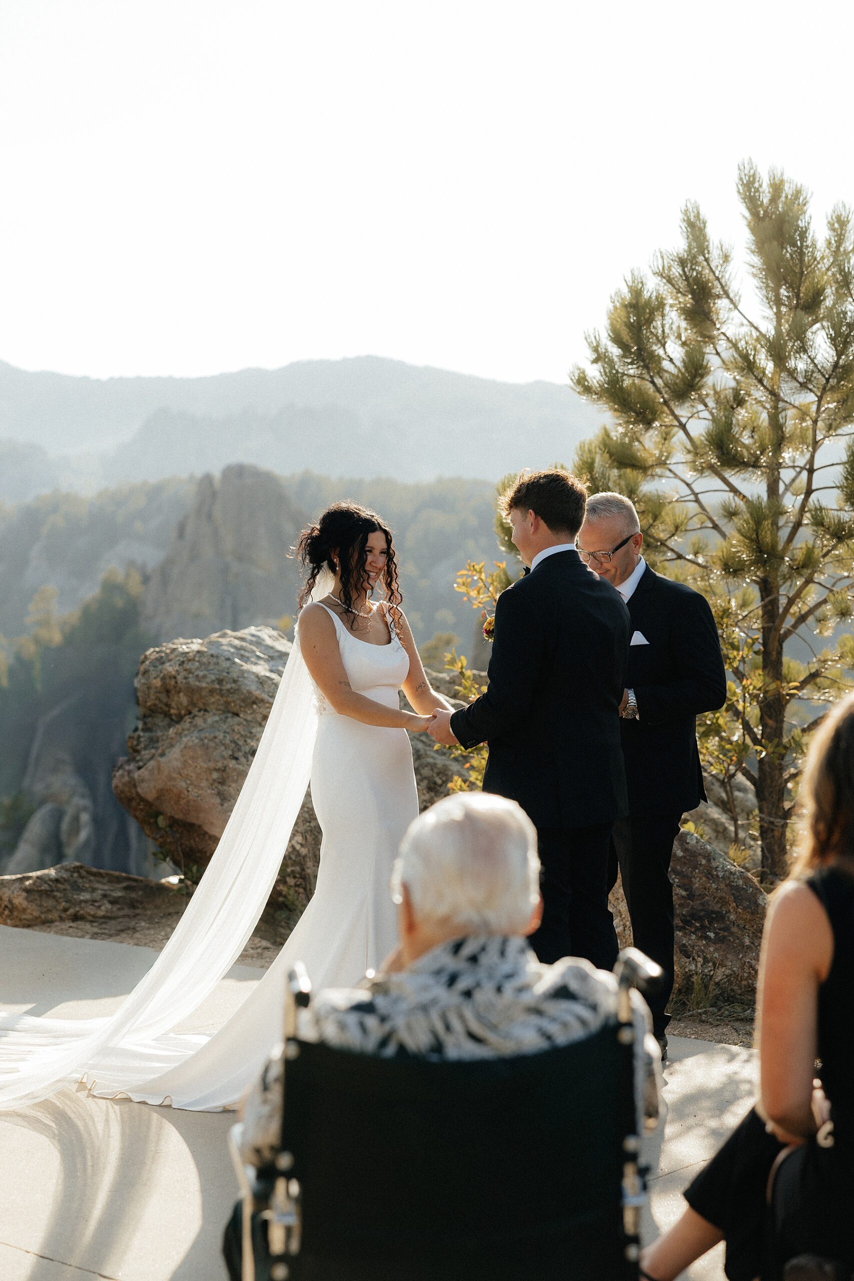 The bride and groom smiling at each other with the views of the black hills in the background.