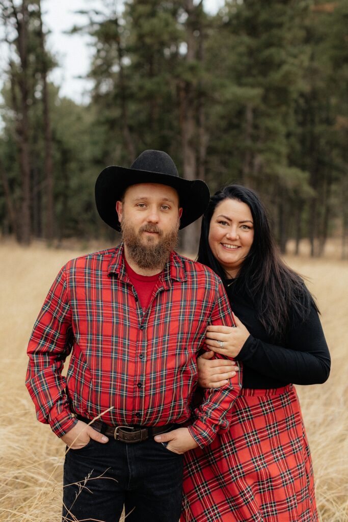 A couple wearing plaid smiling at the camera.