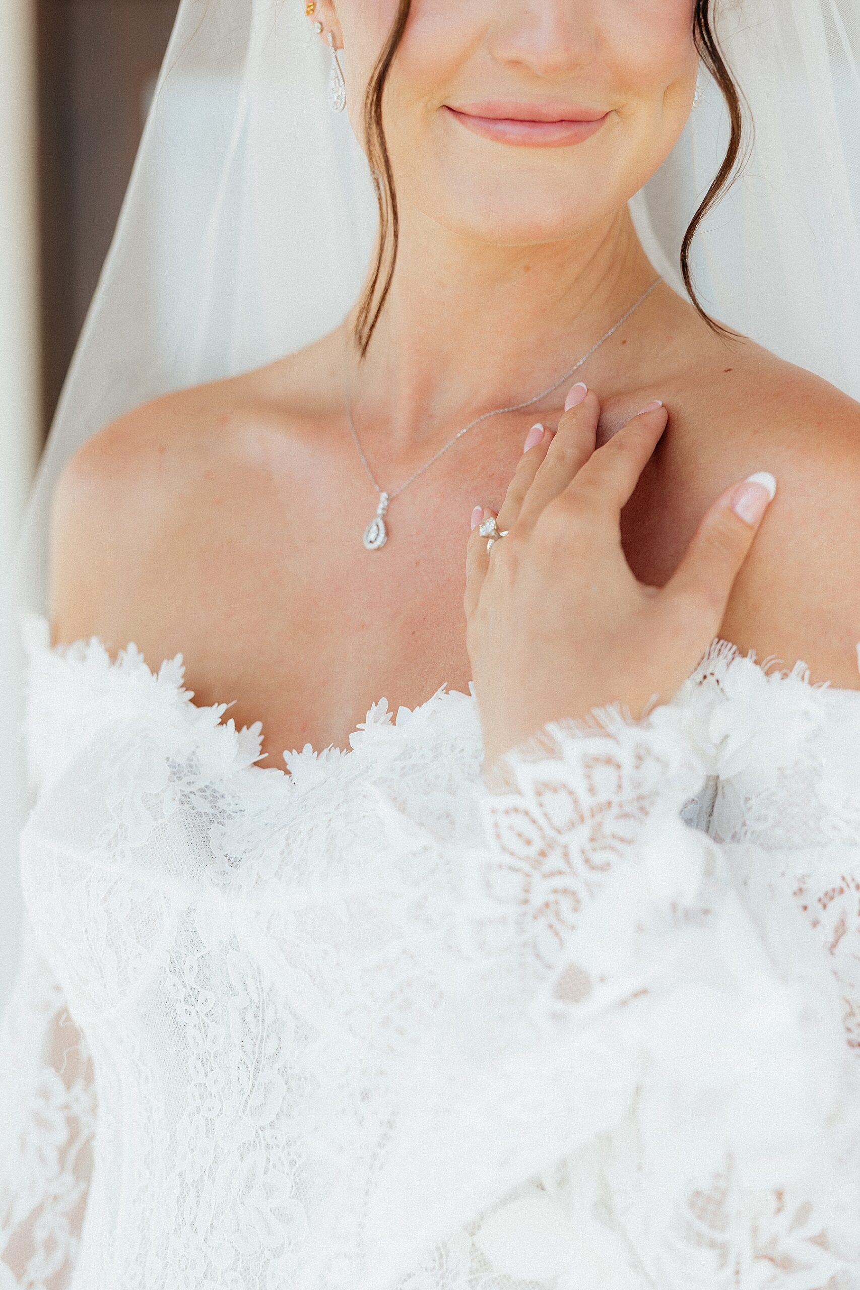A bride resting her hand on her collarbone.