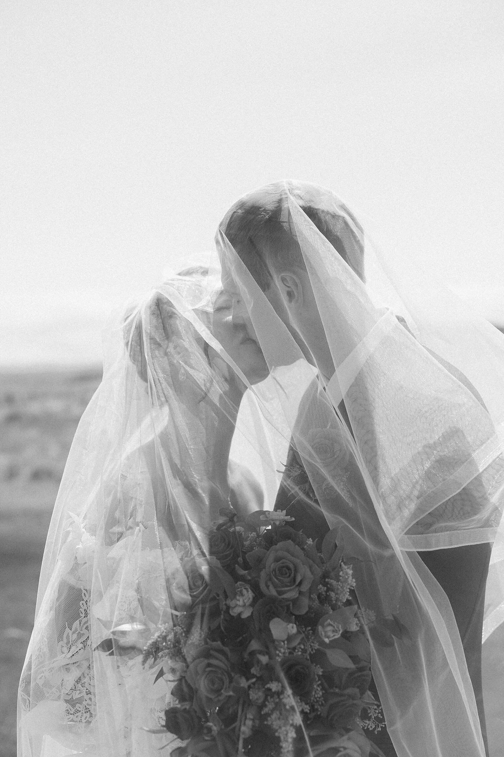 The bride and groom kissing under the veil.