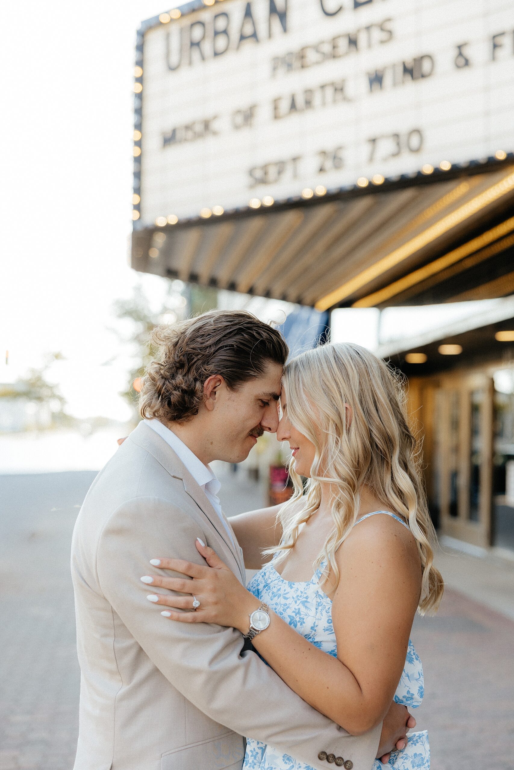 Karissa and Michael standing forehead to forehead in front of an old theatre in downtown St. Cloud.