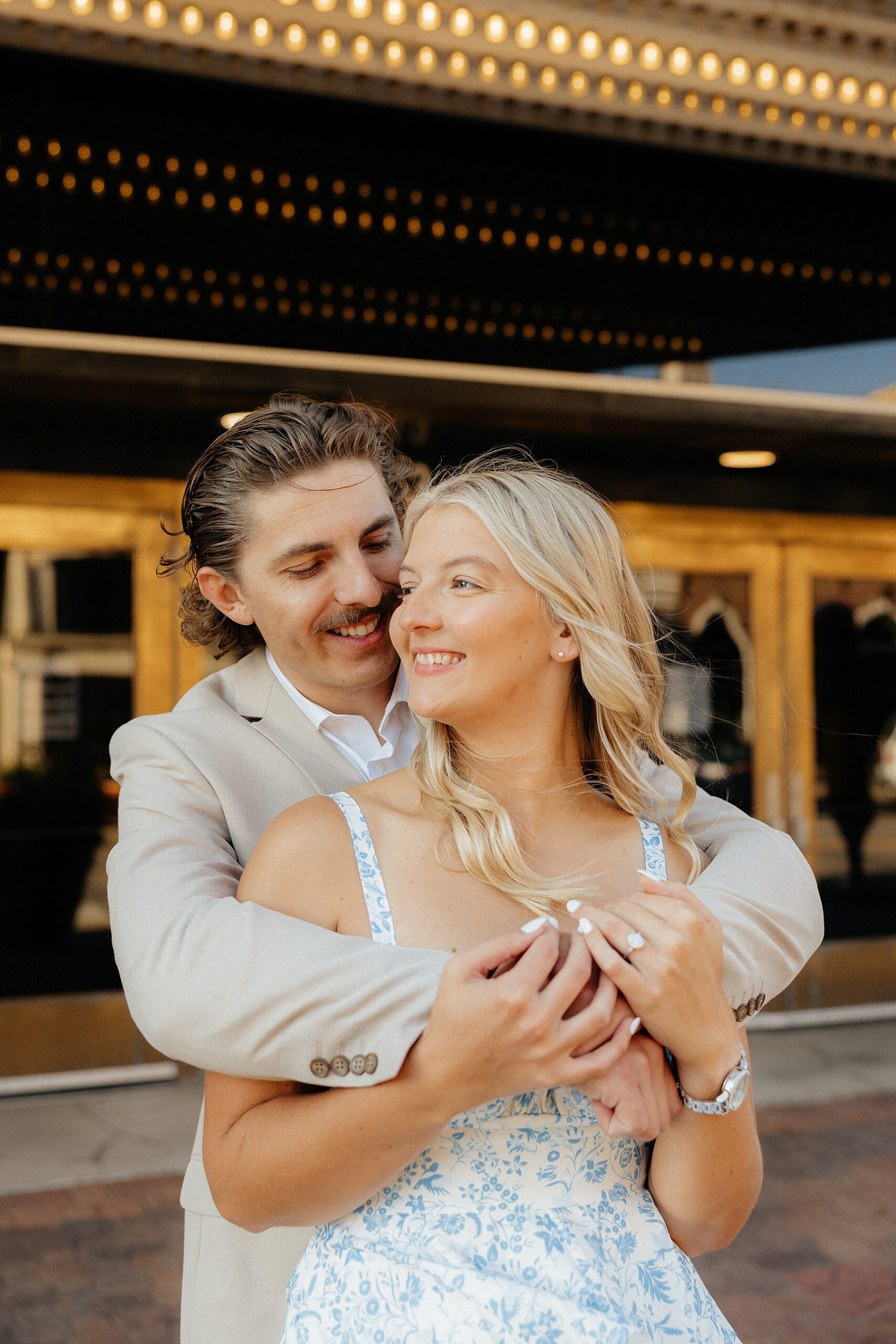 Michael smiling at Karissa in front of a theatre at their creative engagement session.
