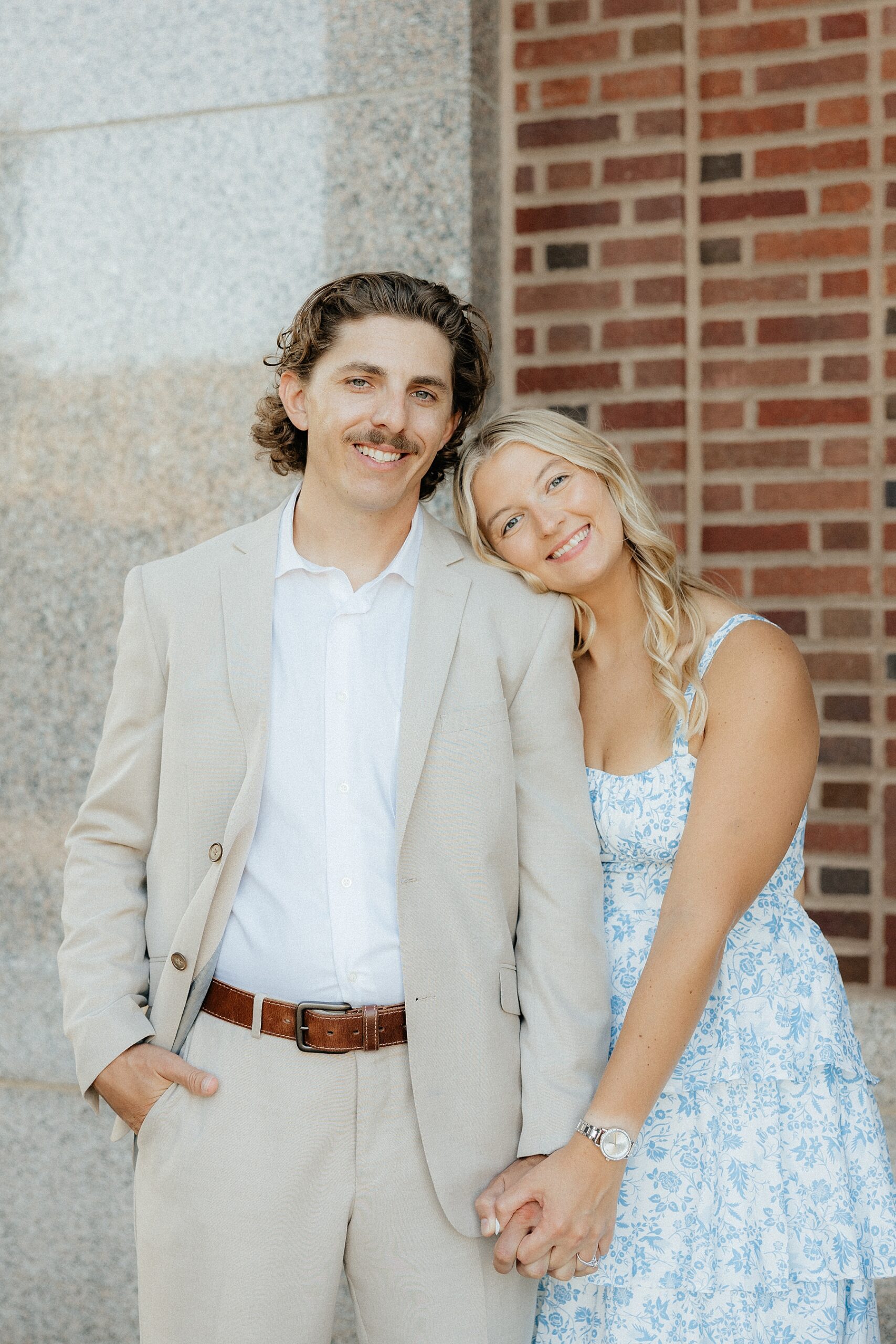 Karissa and Michael smiling in front of the courthouse at their engagement session.