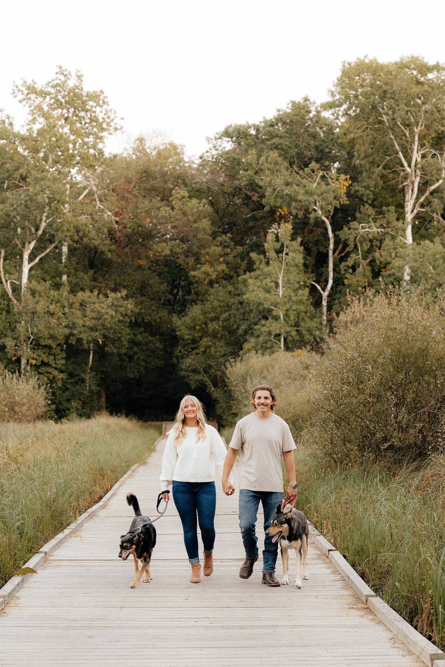 Karissa and Michael walk their dogs on a wood bridge.
