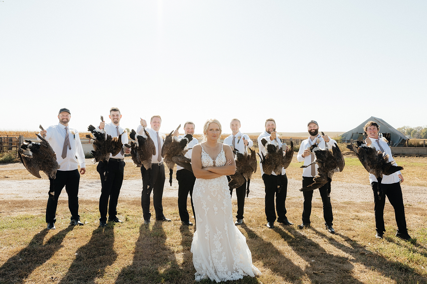 The groom and groomsmen holding up the geese they hunted that morning.