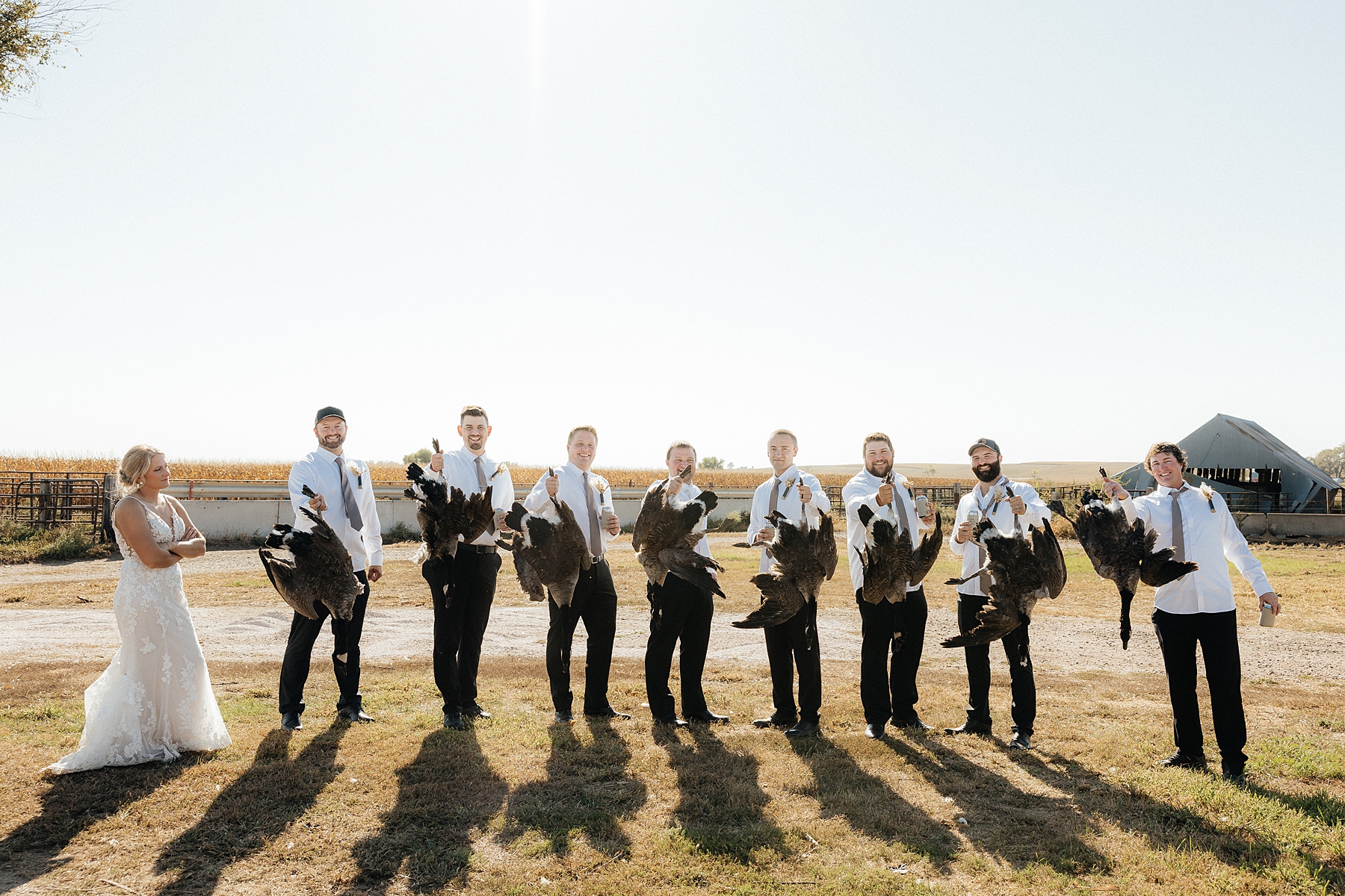 The groom and groomsmen holding up the geese they hunted that morning.