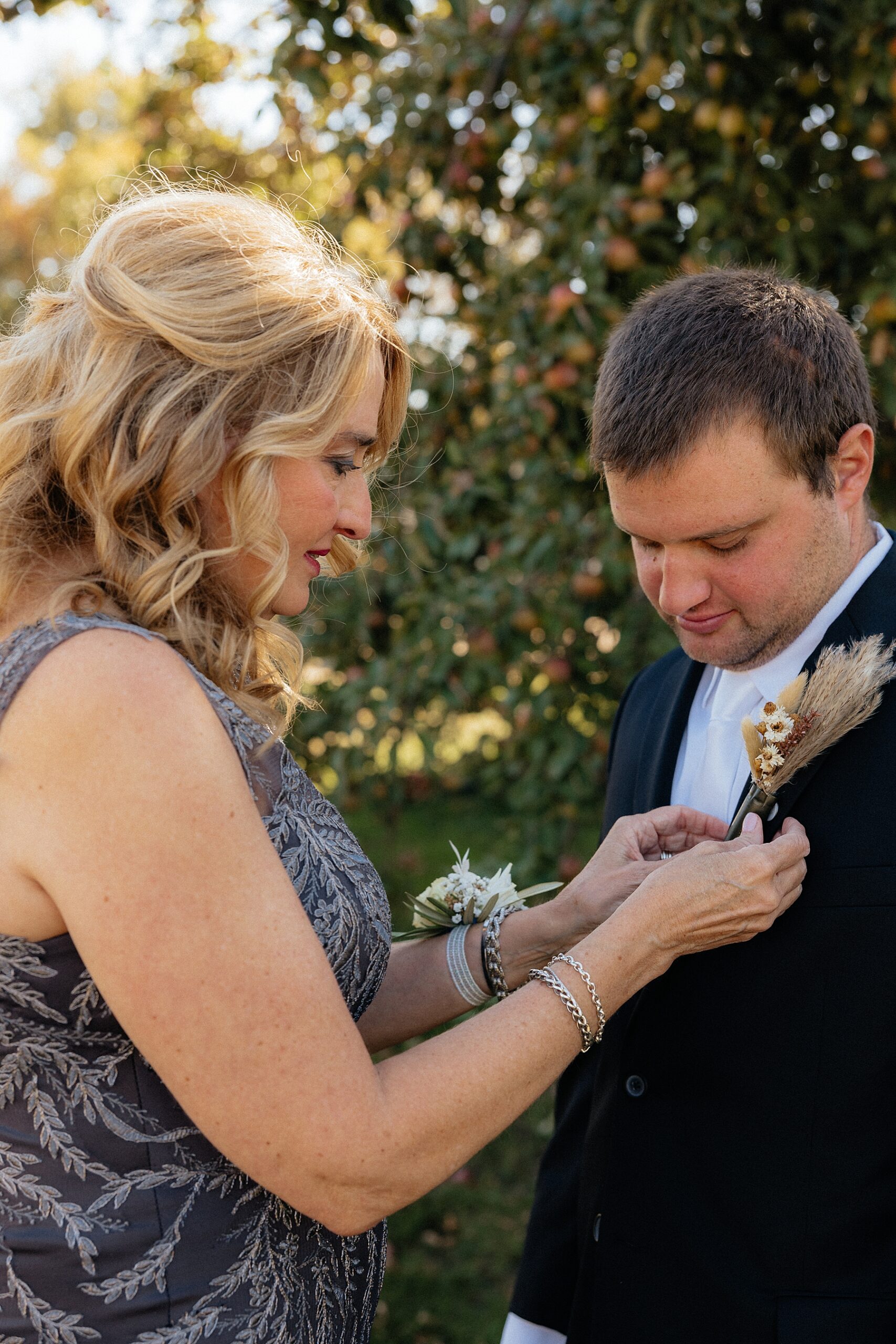 The mother of groom adjusting his boutonniere.
