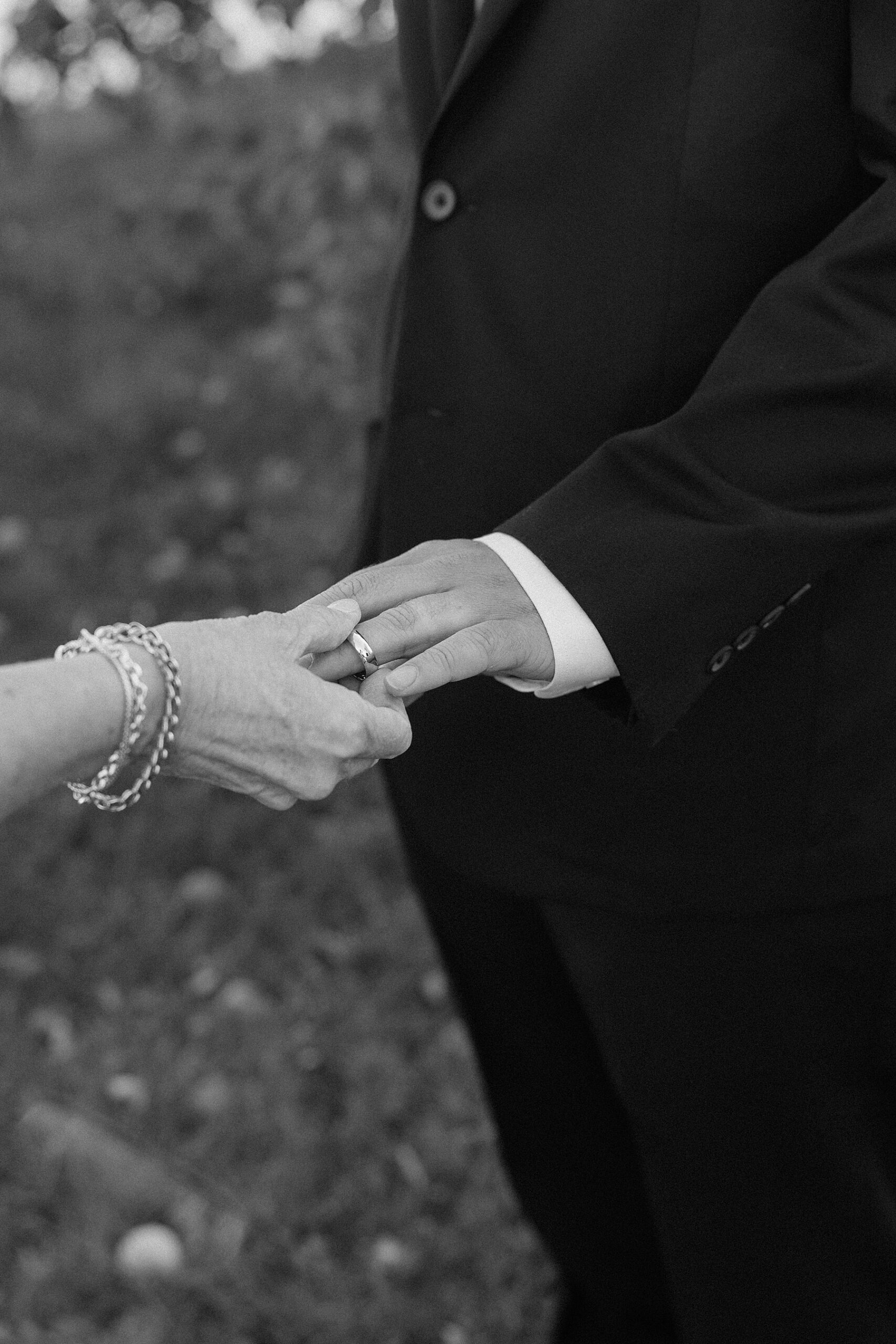 Groom's mother putting on his ring to see if it fits.