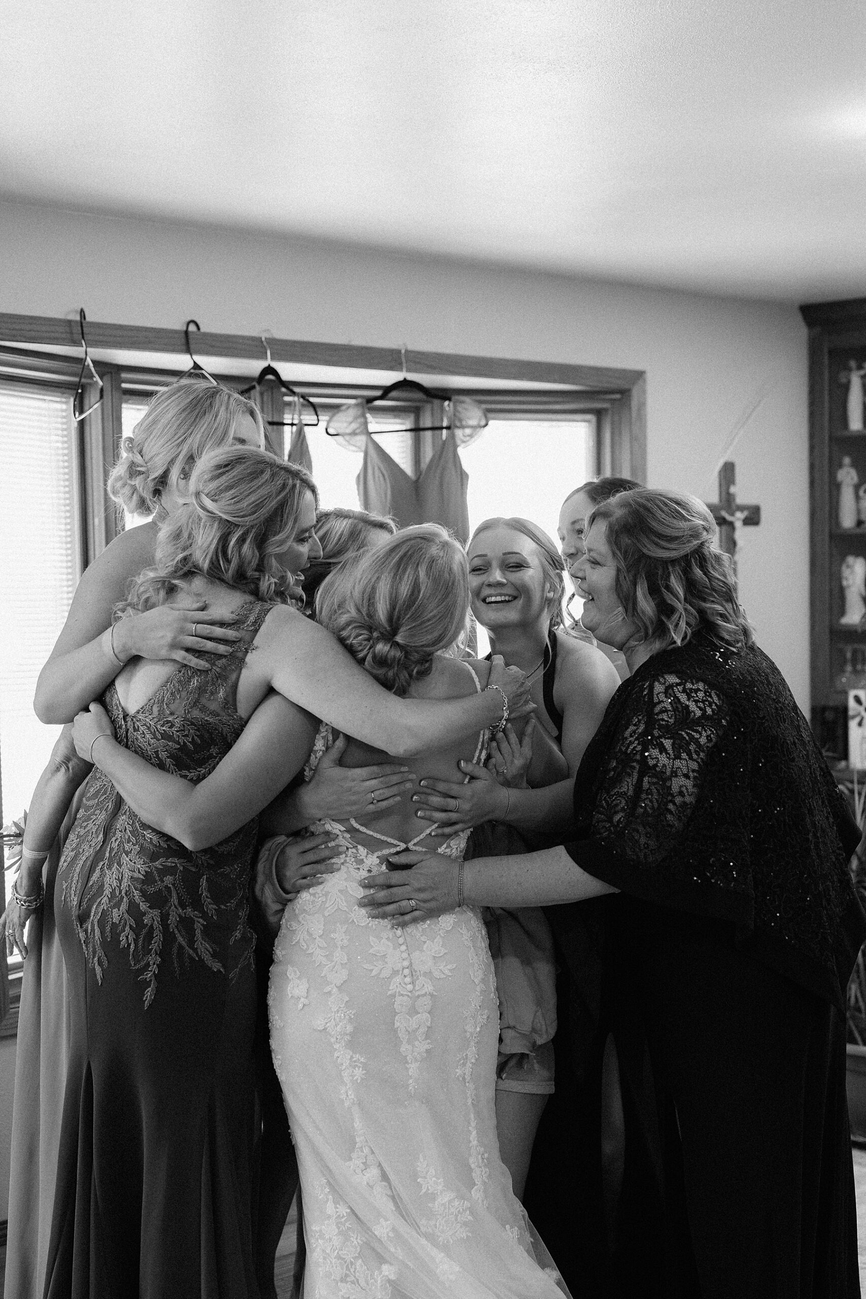 The bridesmaids hugging the bride during their first look of her in the dress.