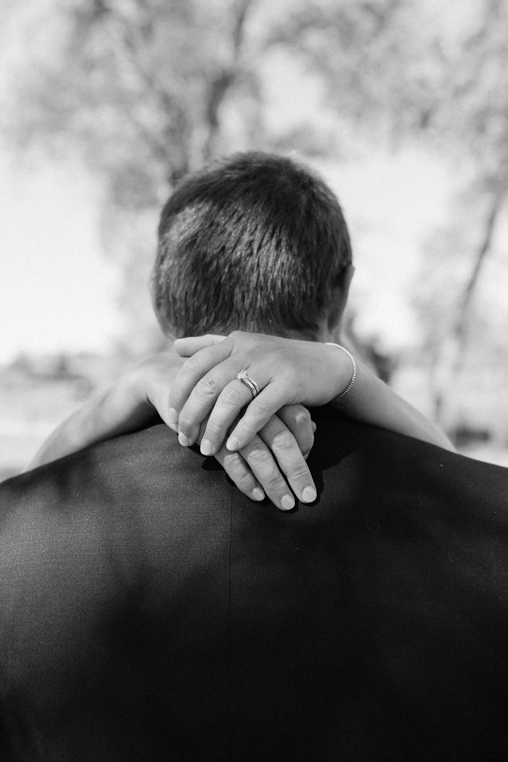 The bride with her arms wrapped around the groom's neck.