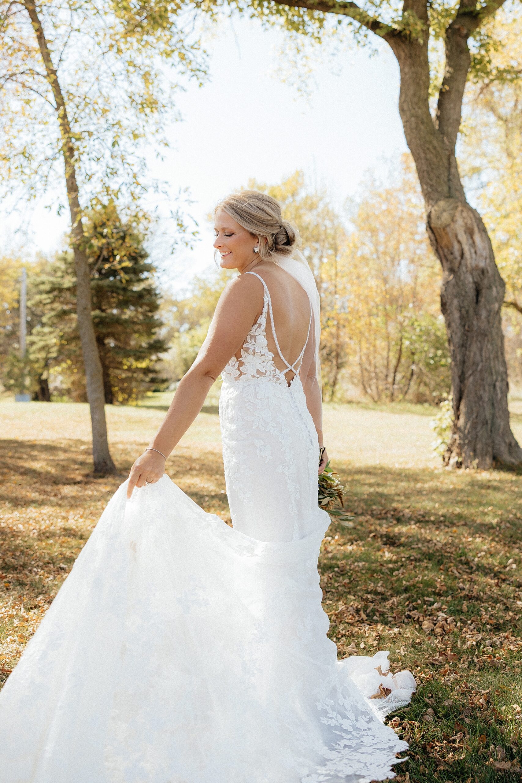 The bride holding the train on her lace dress.