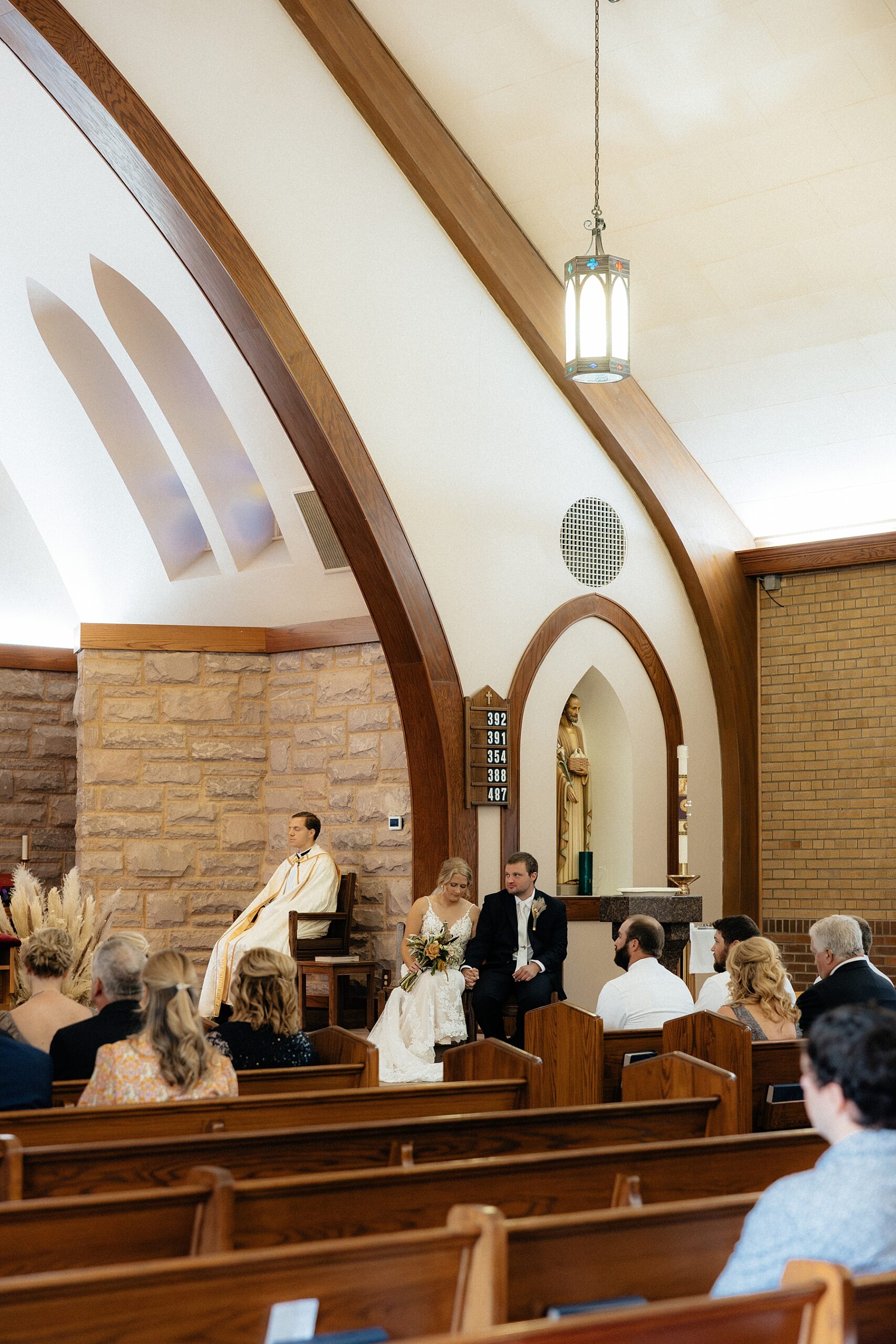 Couple seated facing the audience during the Catholic ceremony
