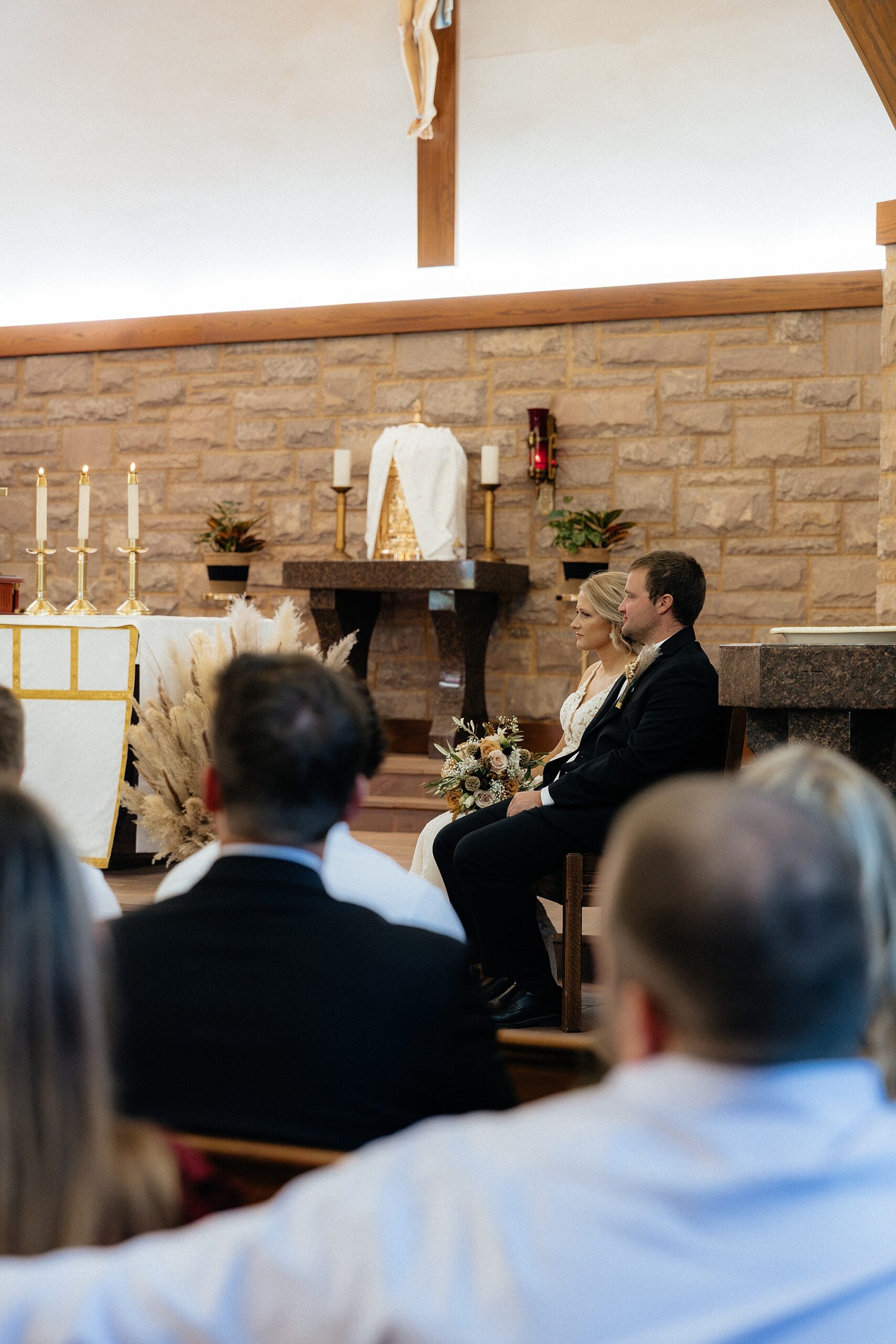 Couple seated facing the audience during the Catholic ceremony