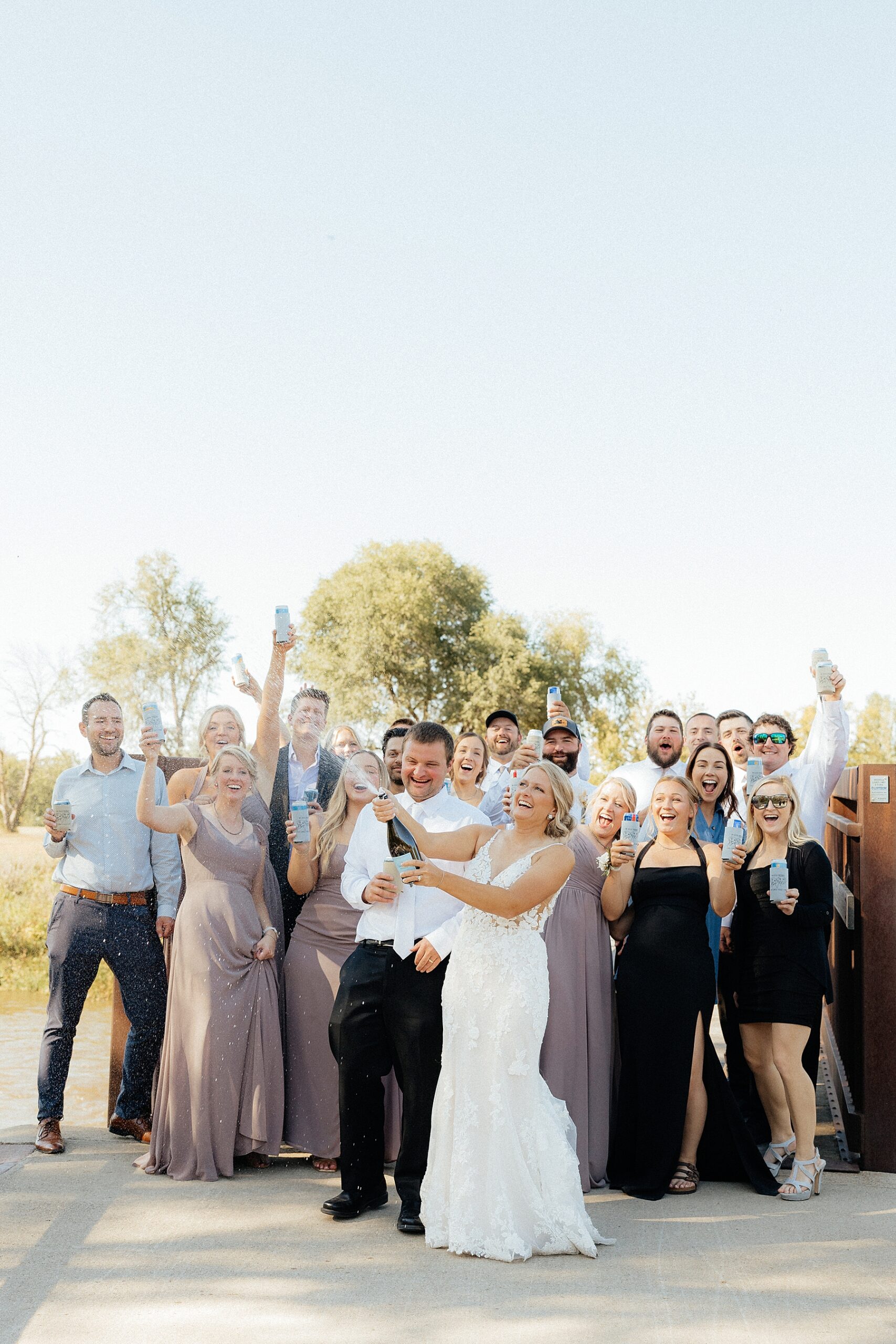 The bride doing a champagne spray in front of the wedding party.