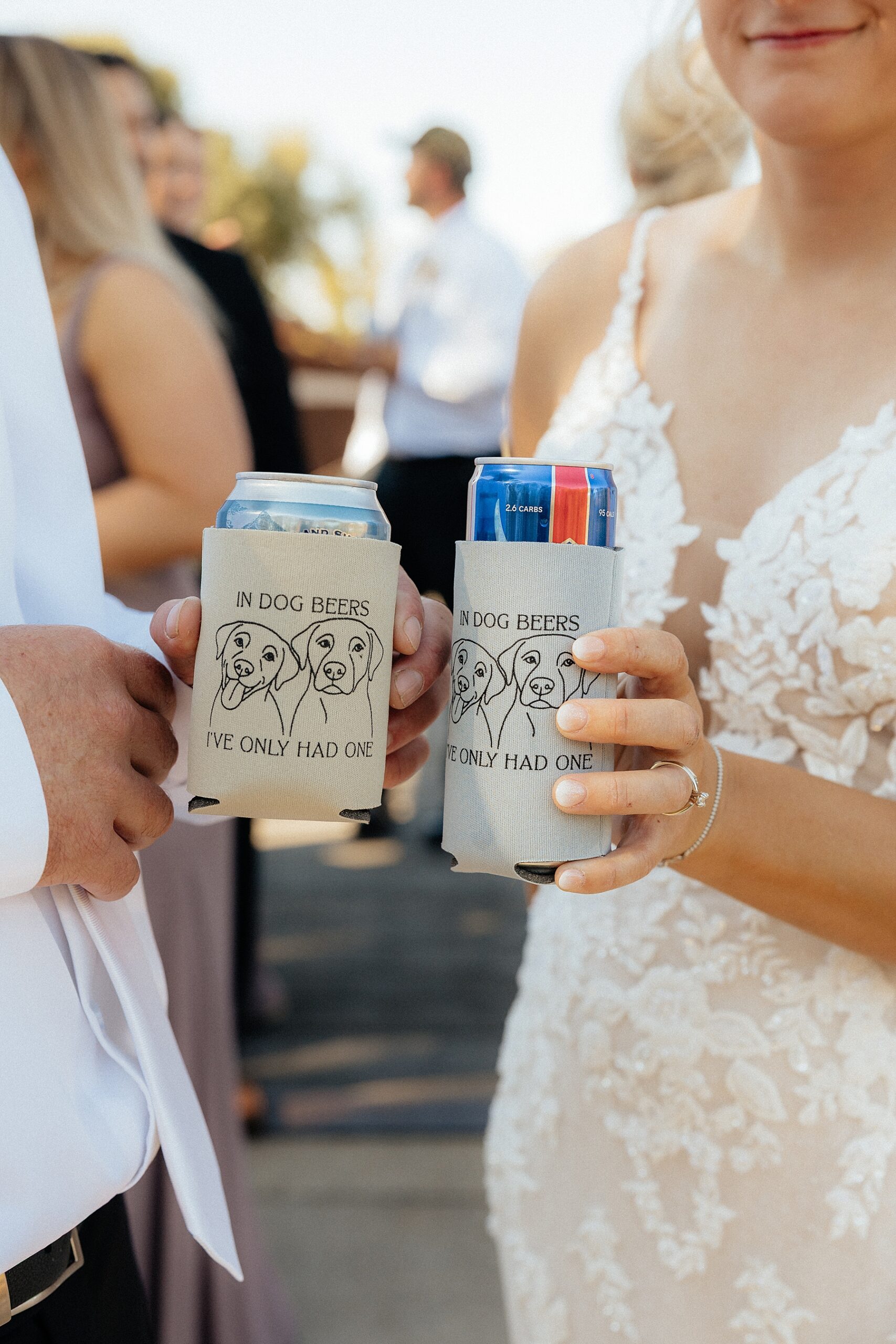 The bride and groom showing off their custom beer coozies with their dogs' faces on it.