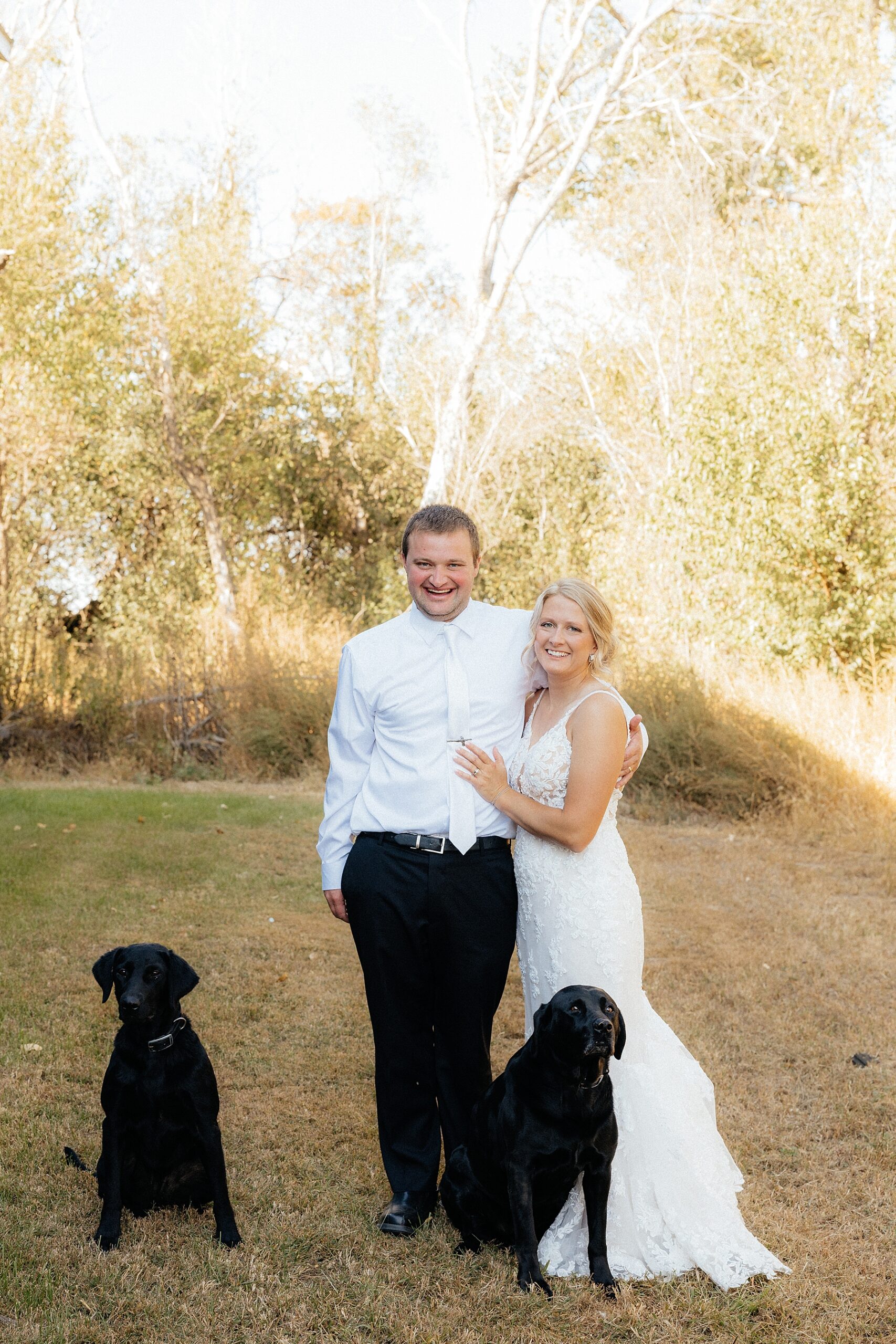 The bride and groom with their two black lab dogs.