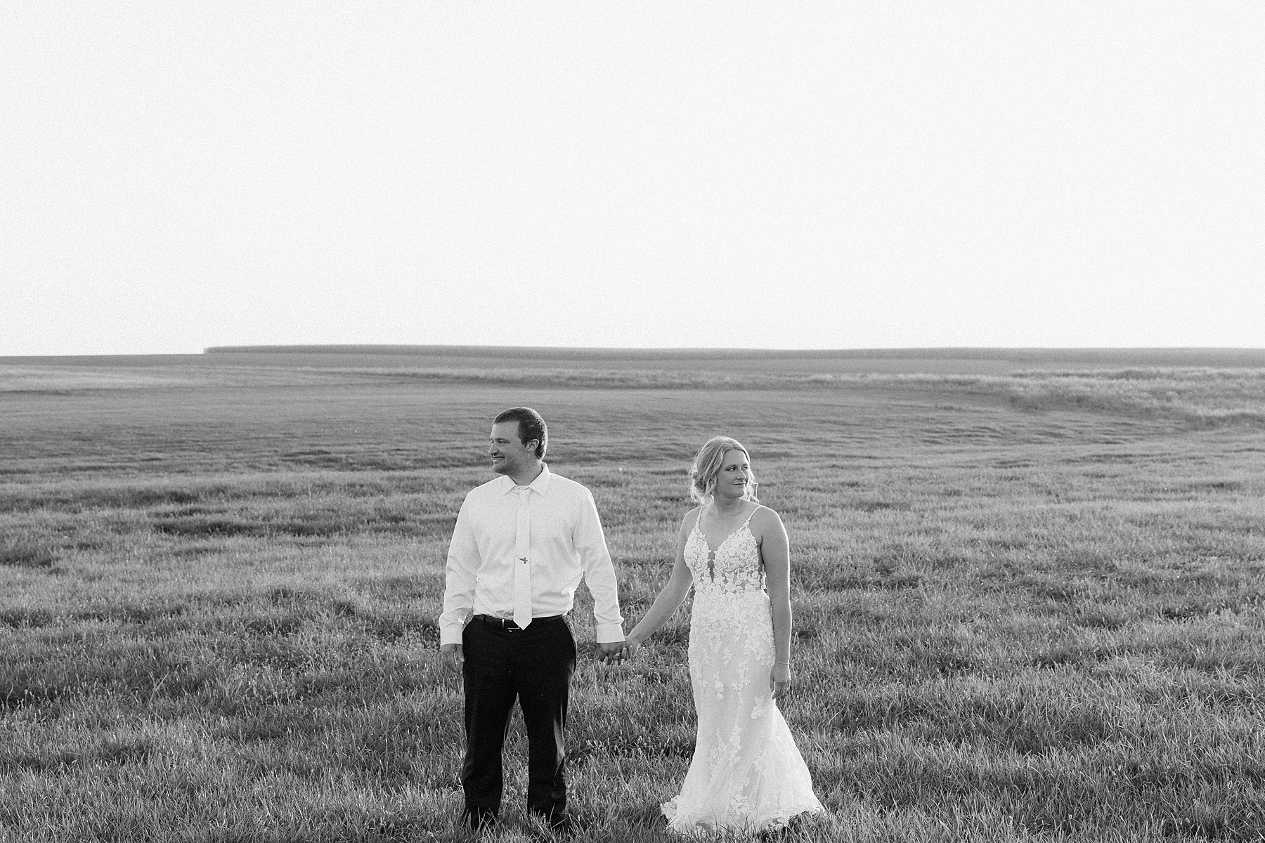 Bride and groom standing in a field looking in the opposite directions