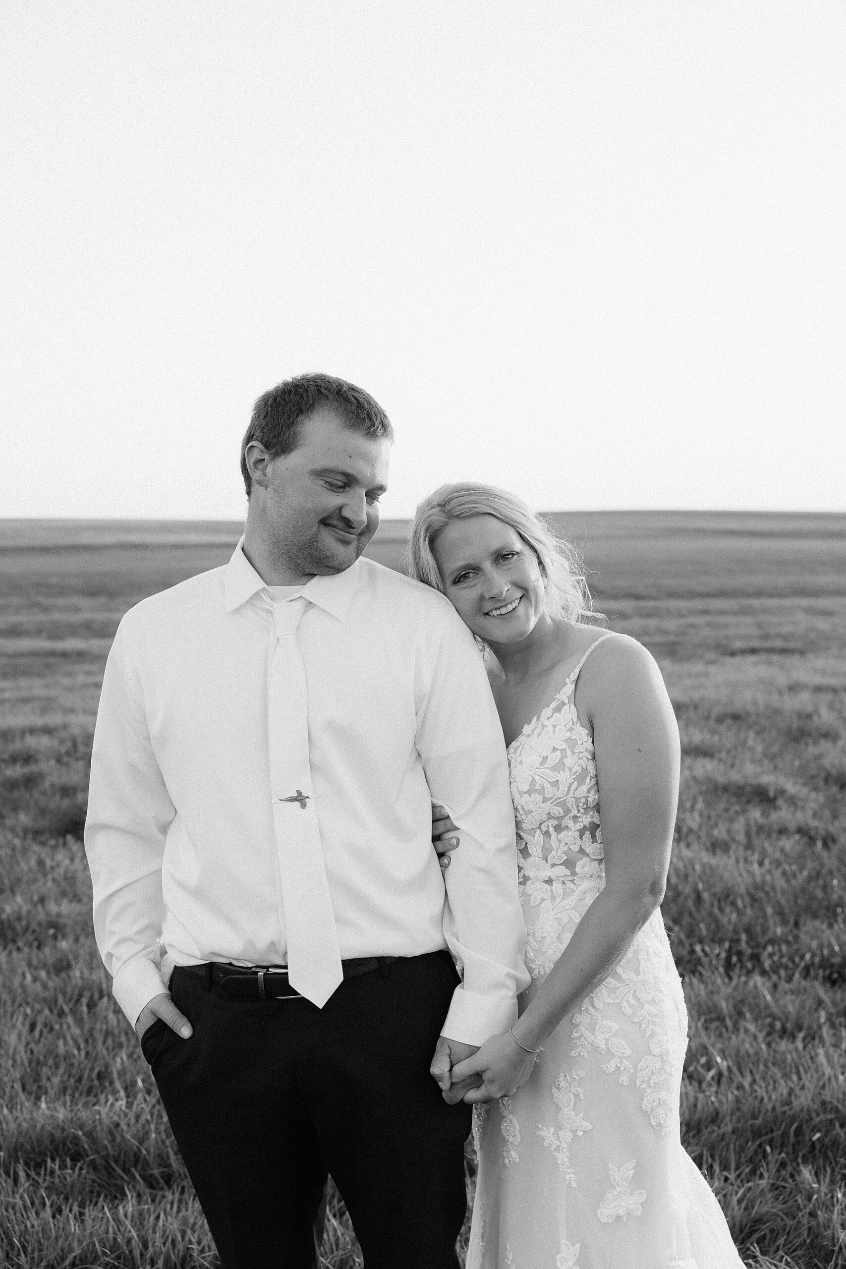 The bride smiling while the groom looks at her.