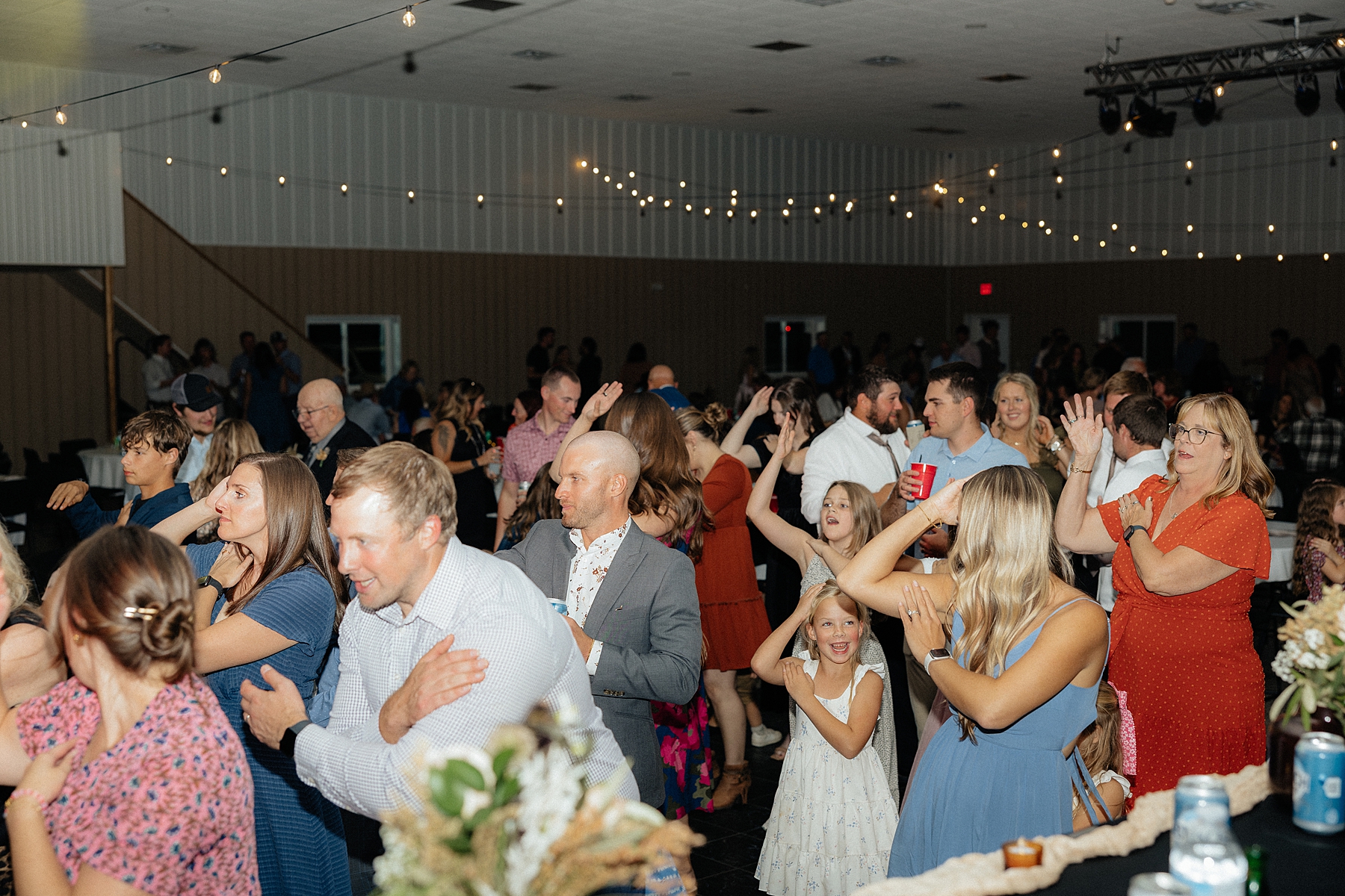 The guests are dancing to the Macarena on the dance floor.