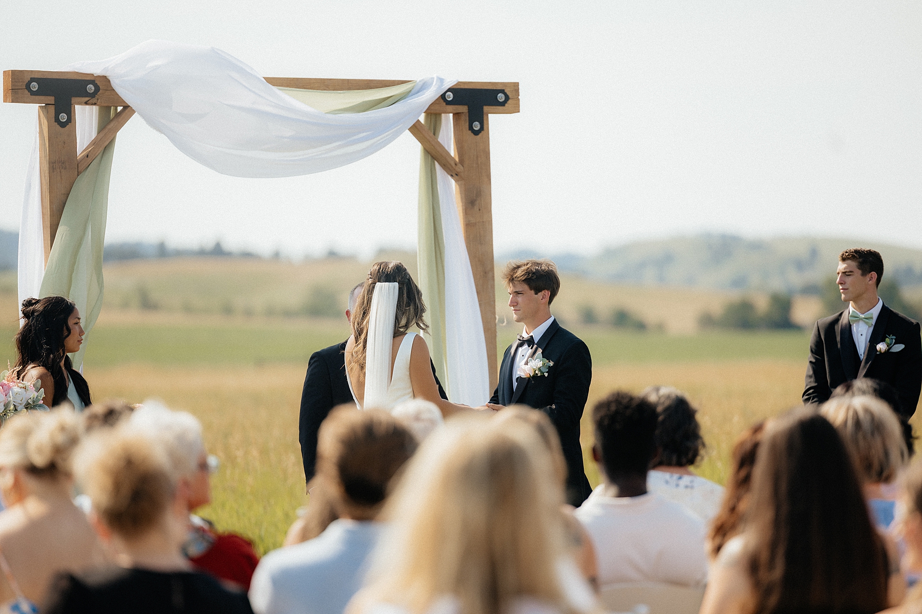 A couple standing hand in hand with the Black Hills in the background at their wedding ceremony.