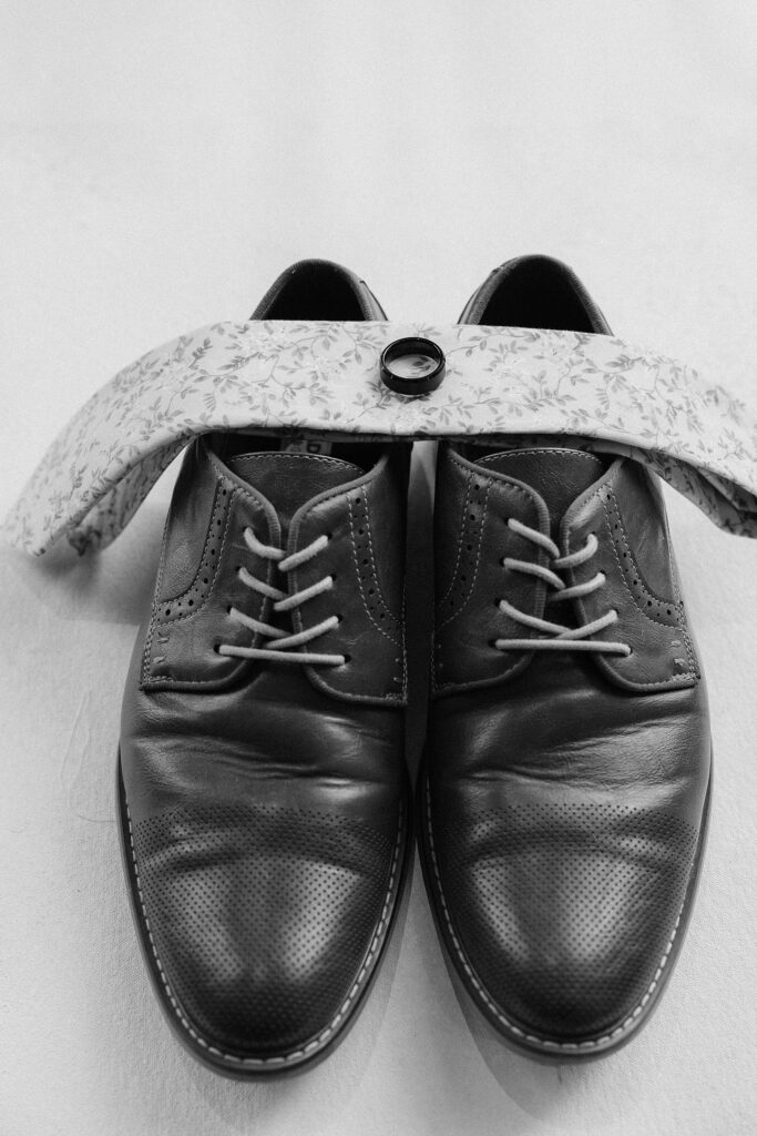 The grooms shoes, tie, and wedding band at a Monick Yards wedding.
