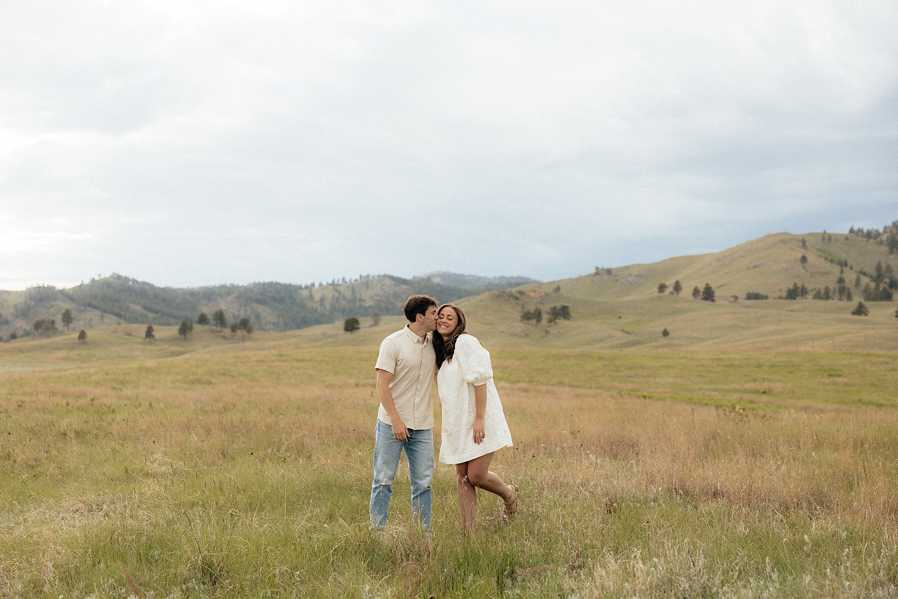Christian kissing Olivia on the cheek during their engagement session in wind cave national park.