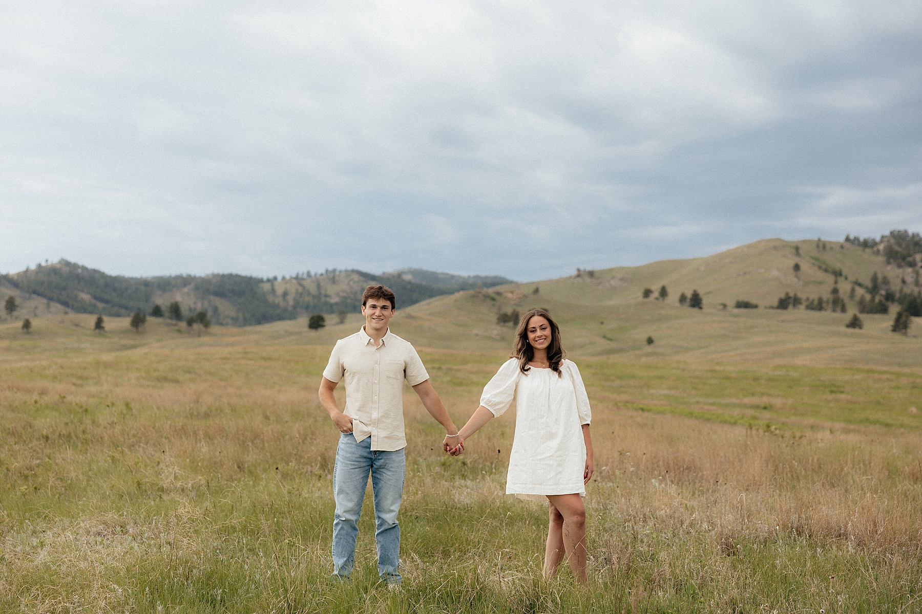 Christian and Olivia smiling at the camera with the Wind Cave landscape behind them.