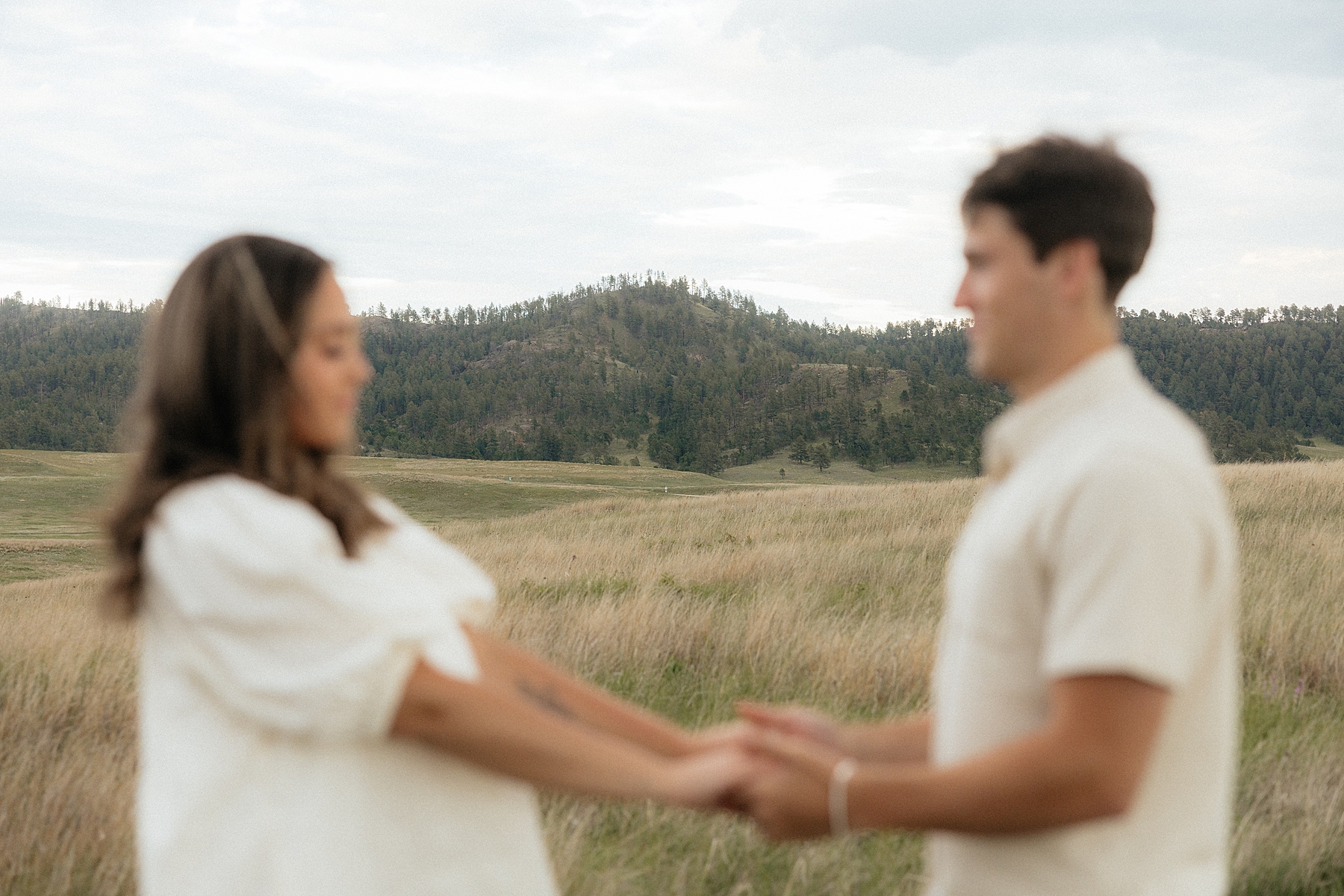 A picture of the couple out of focus with the Black Hills in focus in the background.