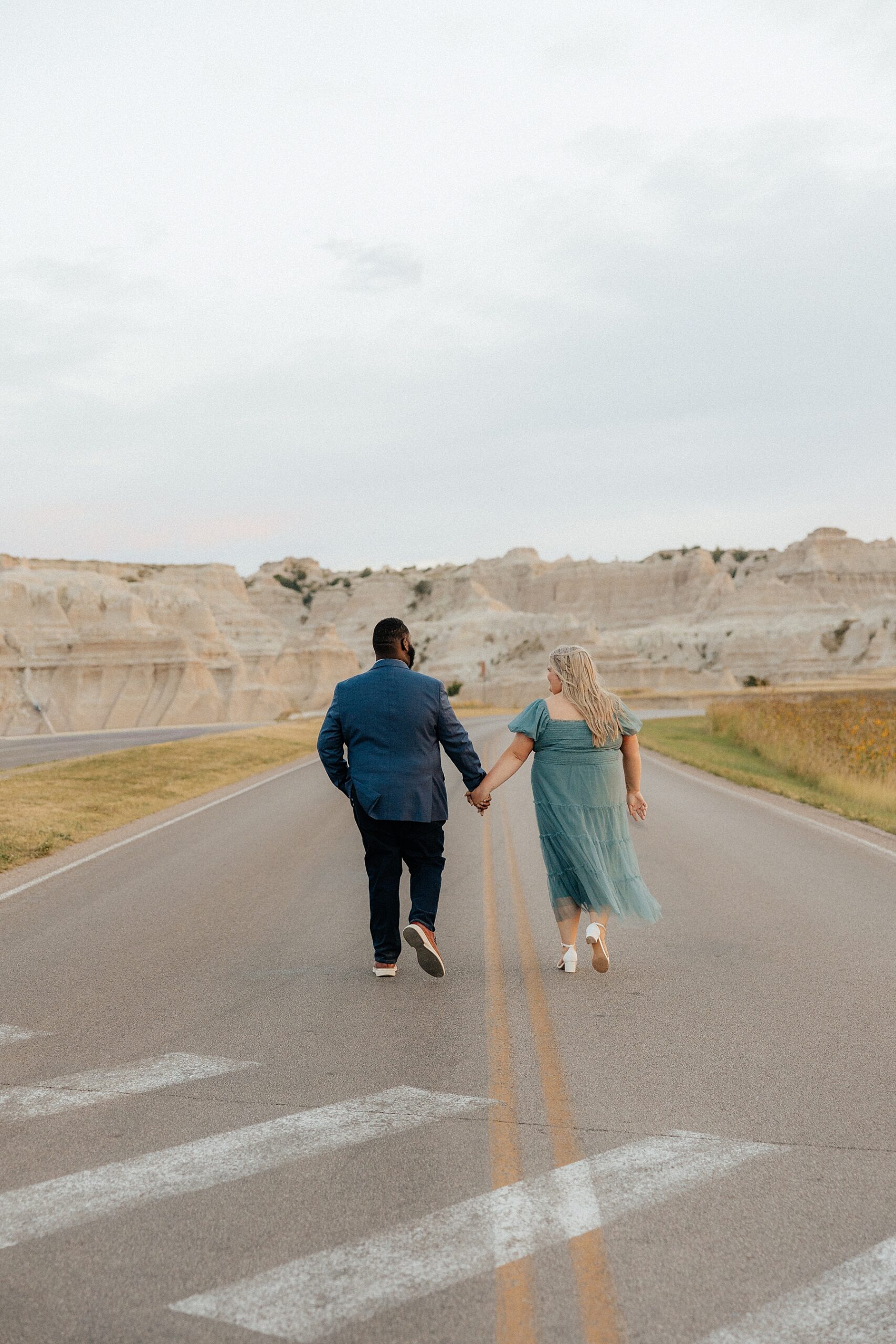 A couple walking on Badlands loop road in Badlands National Park.