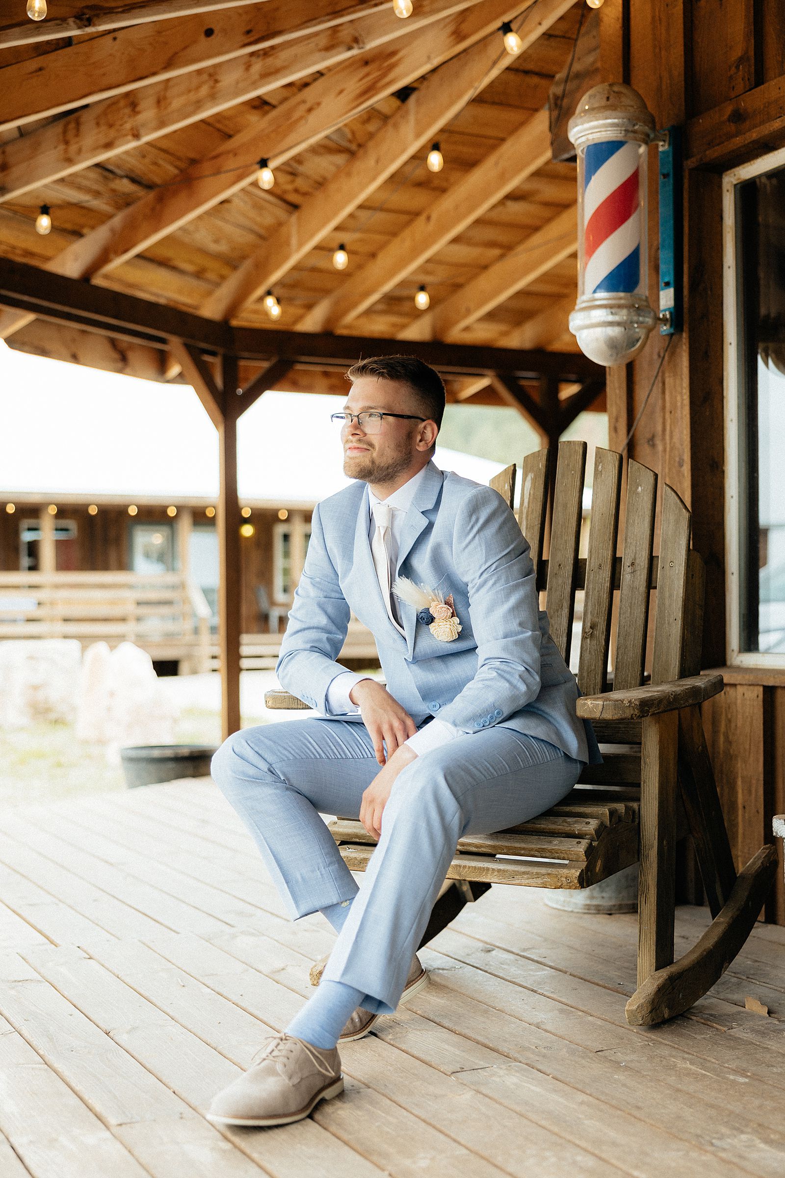 The groom sitting on a chair on the front porch.