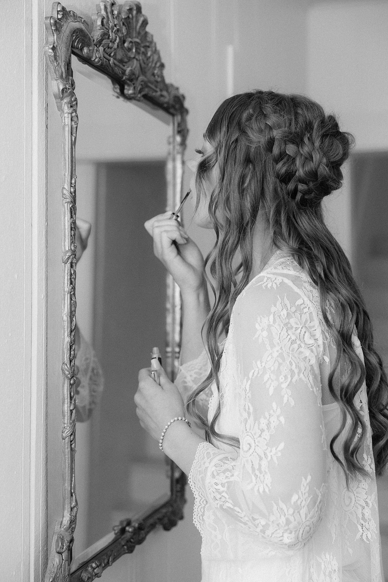 The bride putting on lip gloss in front of a mirror.