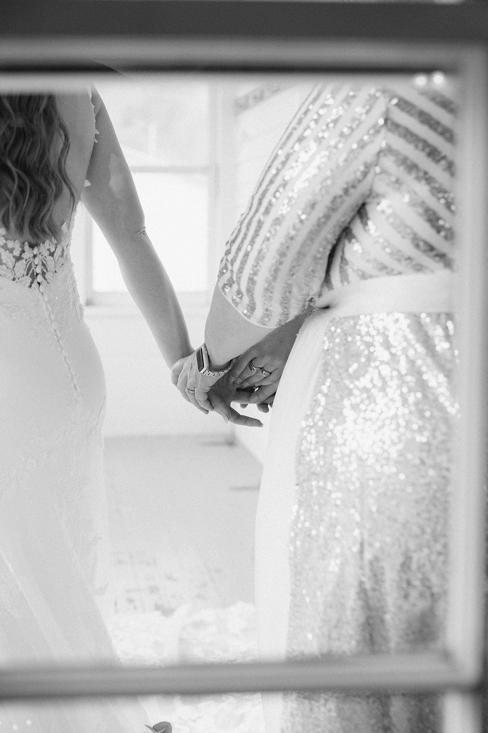 A bride holding hands with her mother and sister at her wedding.