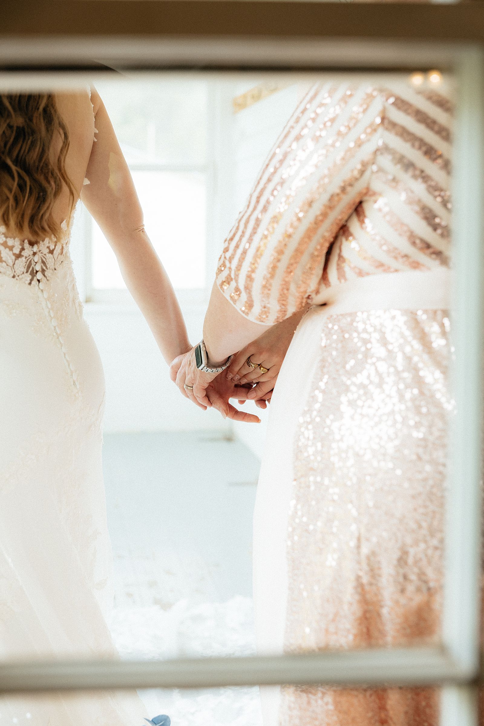 The bride holding hands with her mother and sister.