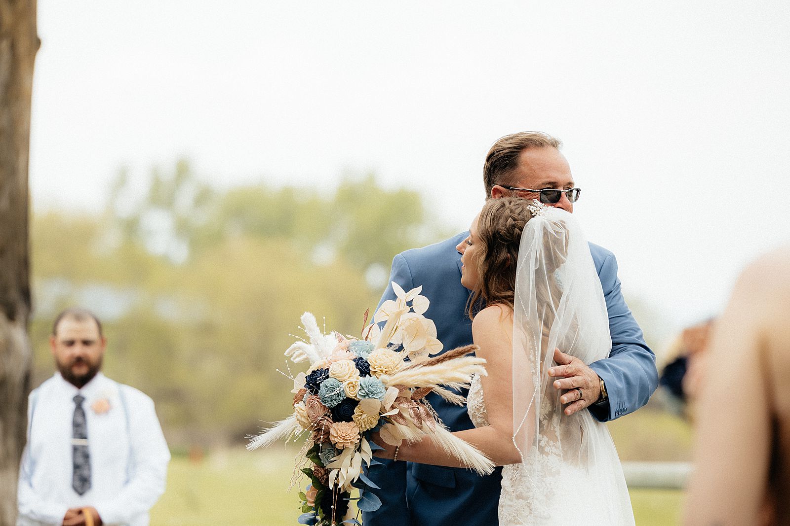 A bride hugging her father as he gives her away. Photo taken by a Black Hills Wedding Photographer.