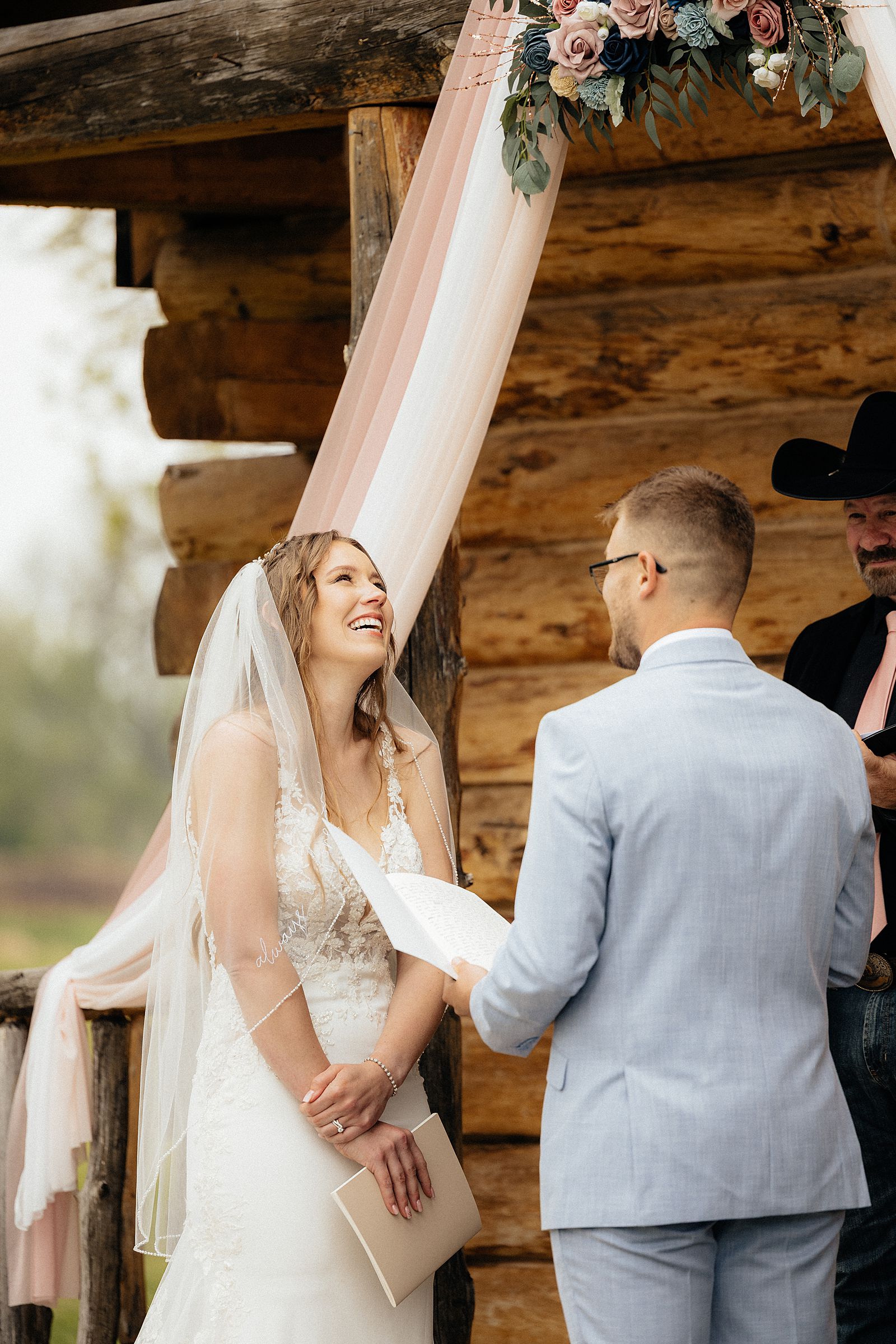 The bride laughing as the groom reads his vows.