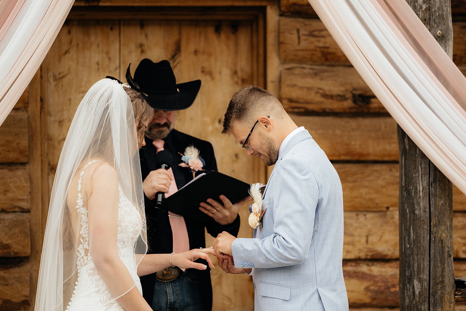 The groom putting on the bride's ring.