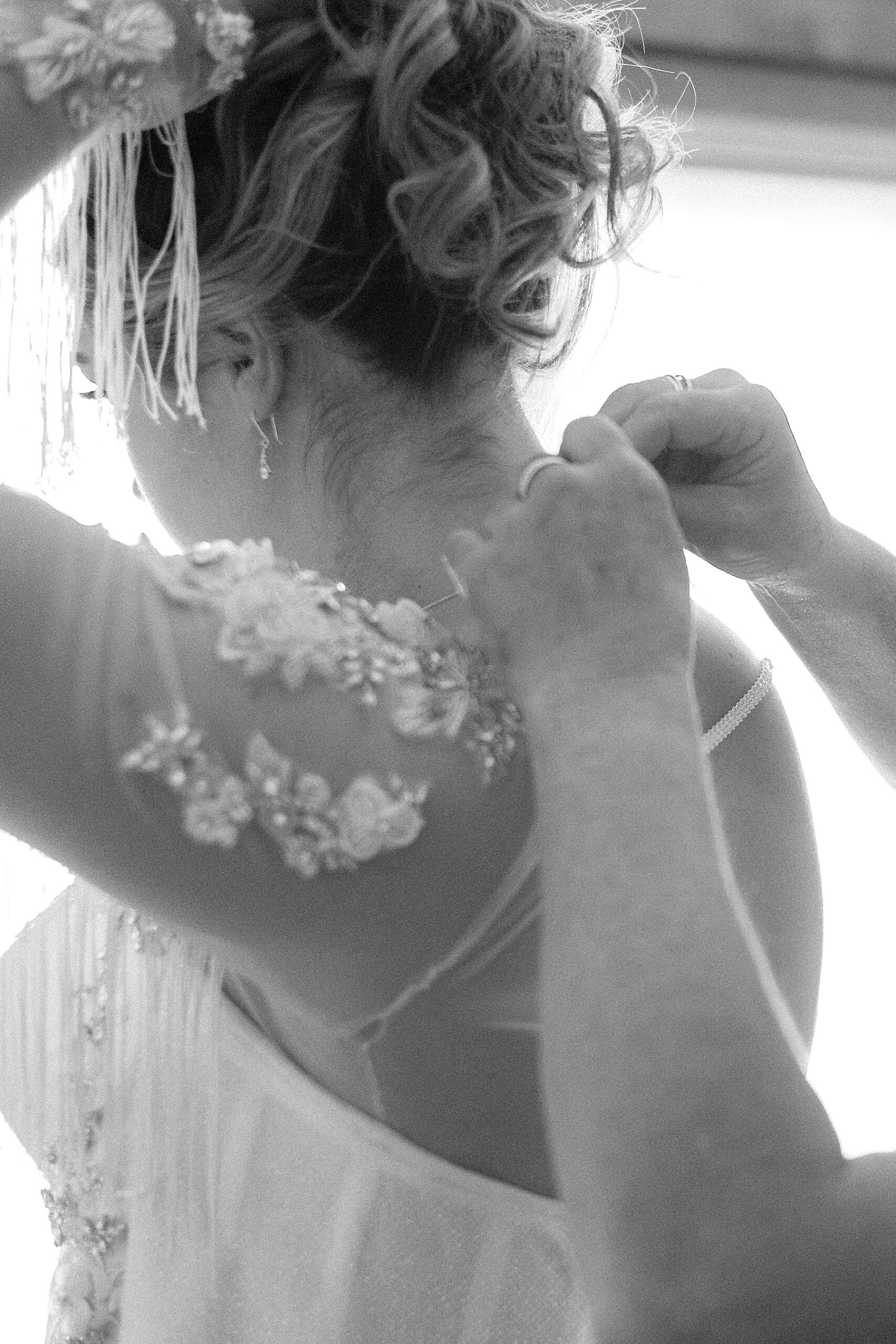 The mother of the bride putting on the bride's necklace.