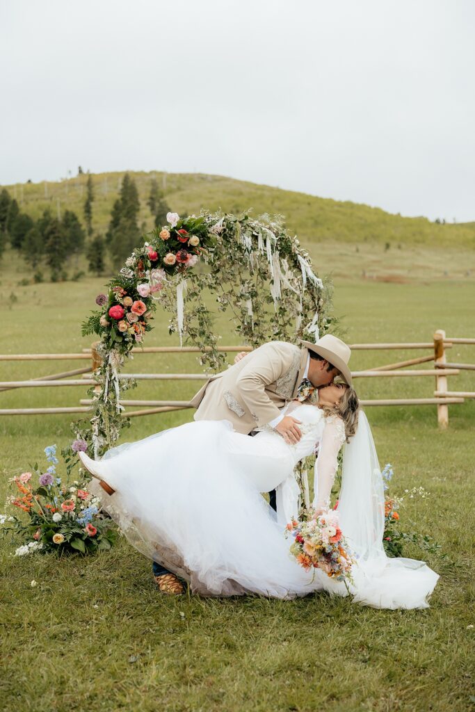 The groom dipping the bride in front of the ceremony space.