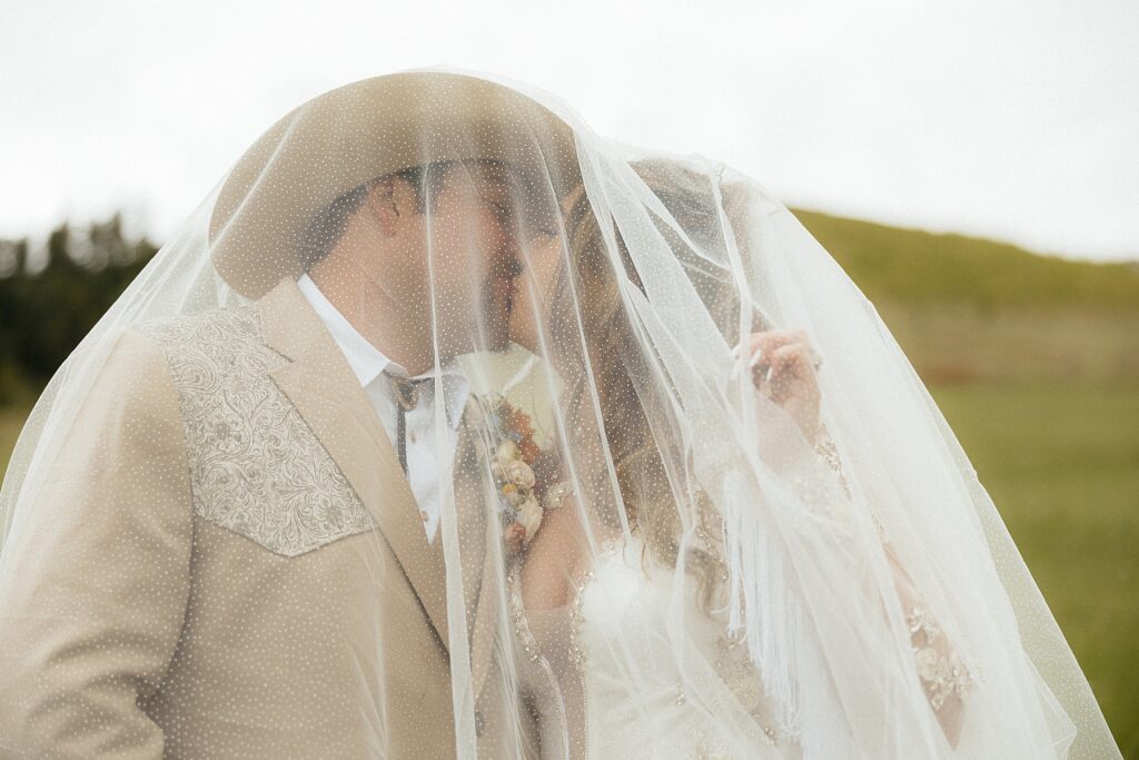 The bride and groom kissing under the truck.